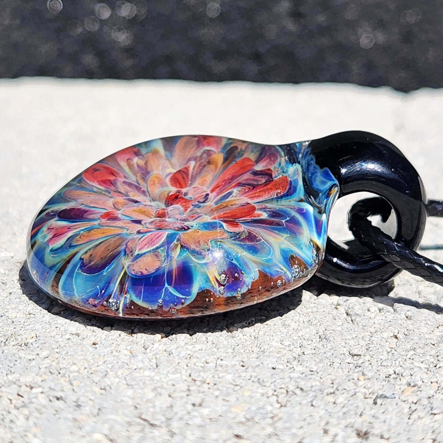 Colorful flower design in handmade glass pendant necklace. Unique lampworked jewelry gift with blue and red tones.