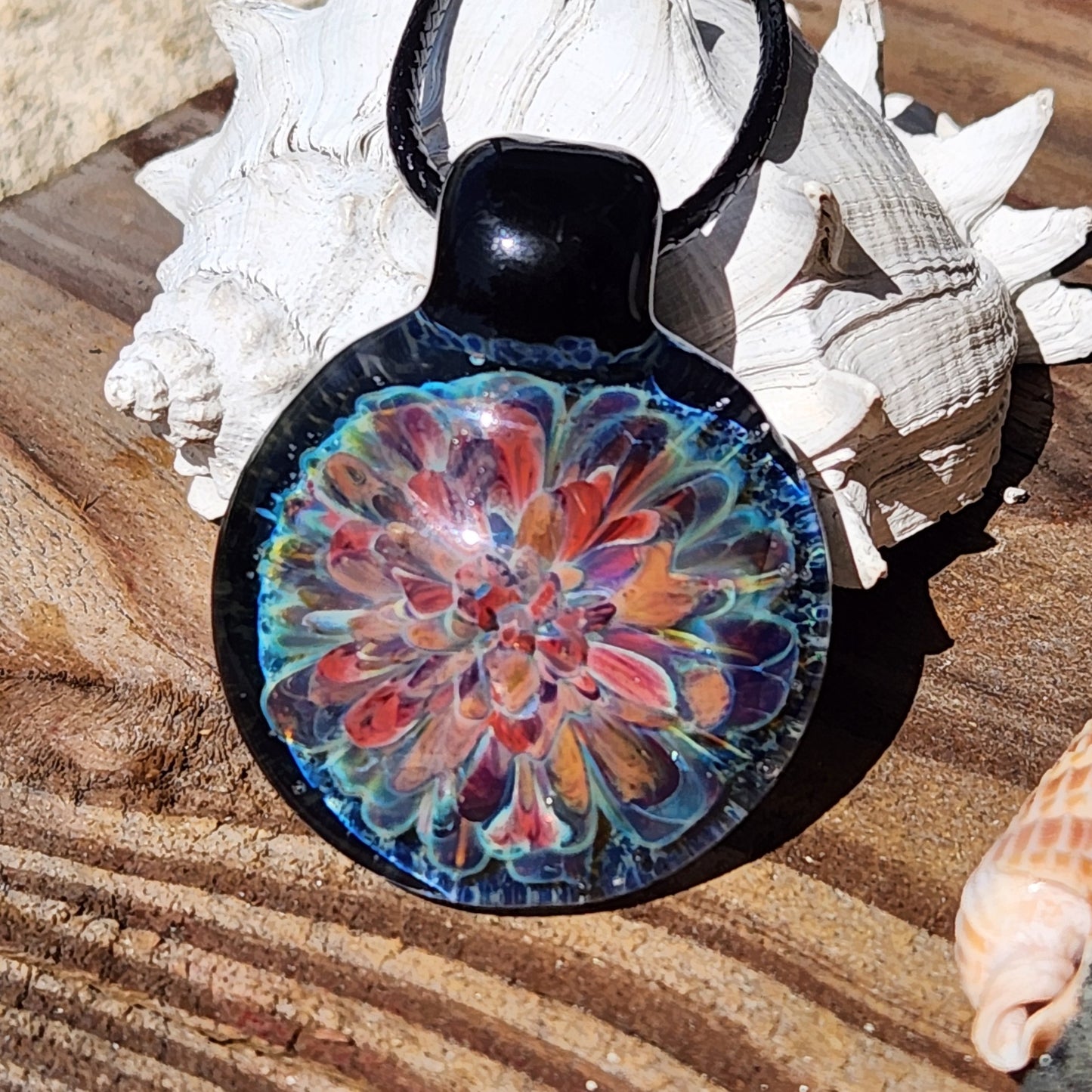 Front view of artisan glass pendant necklace with red, orange, and blue floral pattern. Handmade jewelry gift idea.