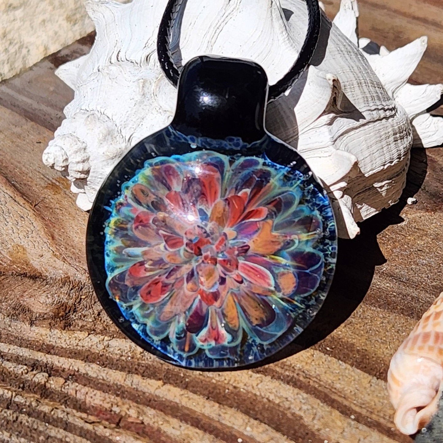 Front view of artisan glass pendant necklace with red, orange, and blue floral pattern. Handmade jewelry gift idea.
