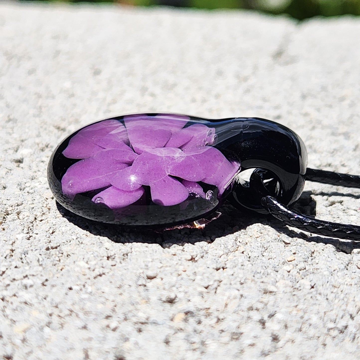 Angled view of minimalist purple and black glass pendant with floral motif, handmade in the USA and ideal for everyday wear.