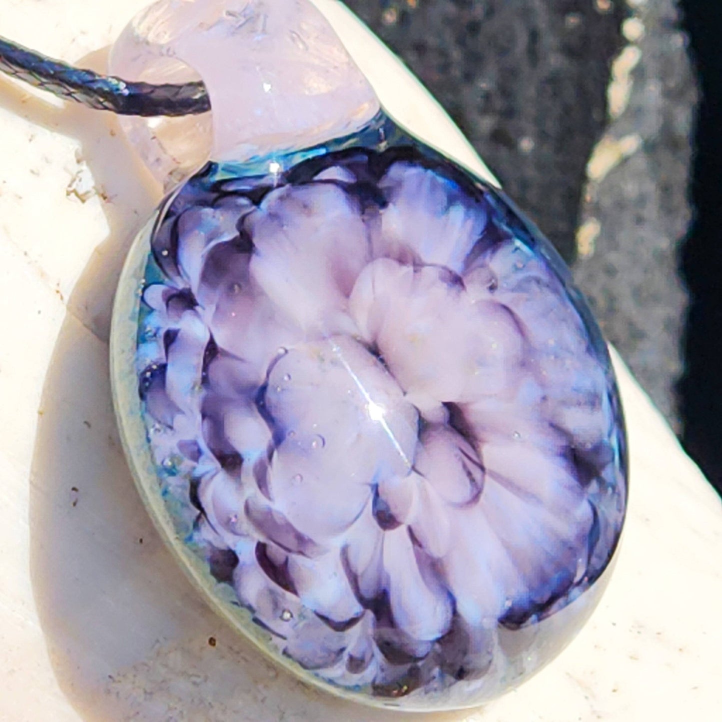 Detailed side view of handmade pink flower pendant necklace with visible glass texture and layered petal design.