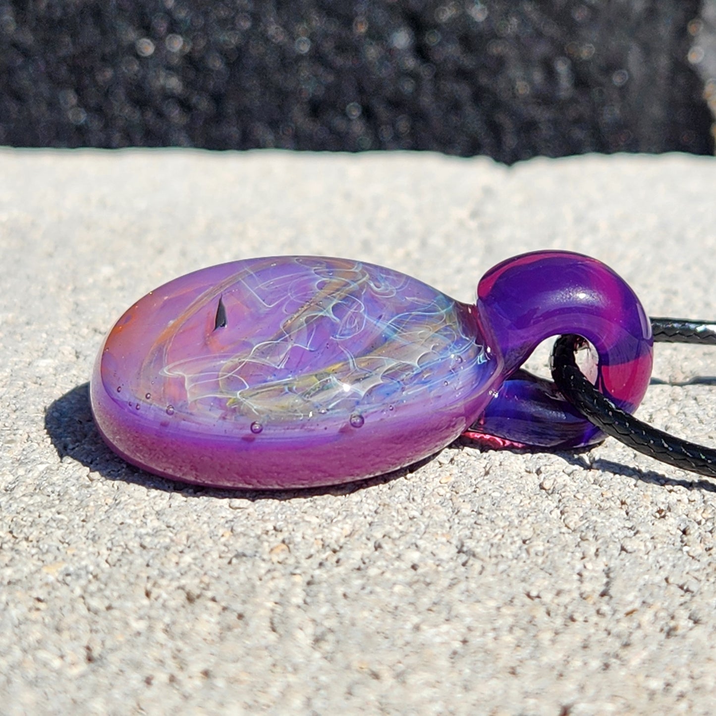 Side angle of purple glass pendant necklace with silver and gold fuming. Unique artisan jewelry with a smooth finish.