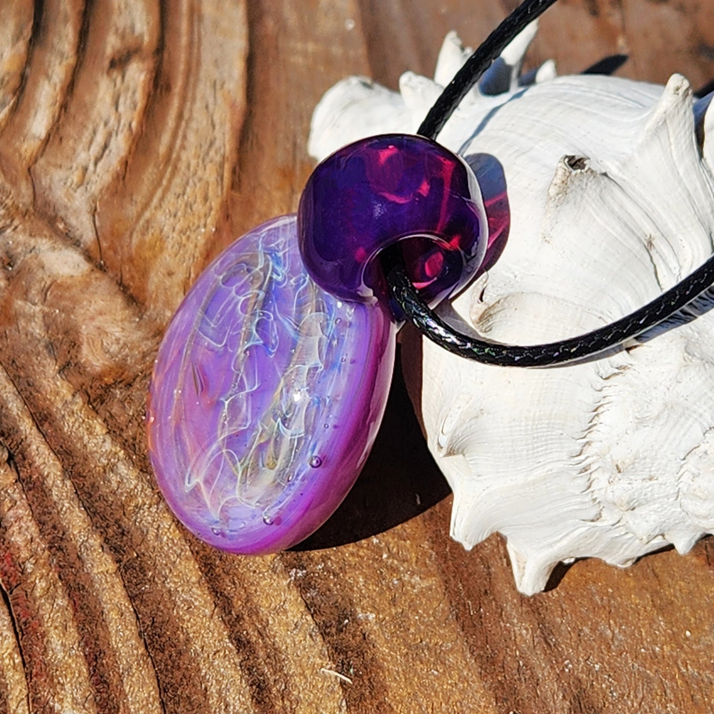 Detailed view of purple glass pendant with swirling fumed patterns. Handmade necklace with silver and gold accents.