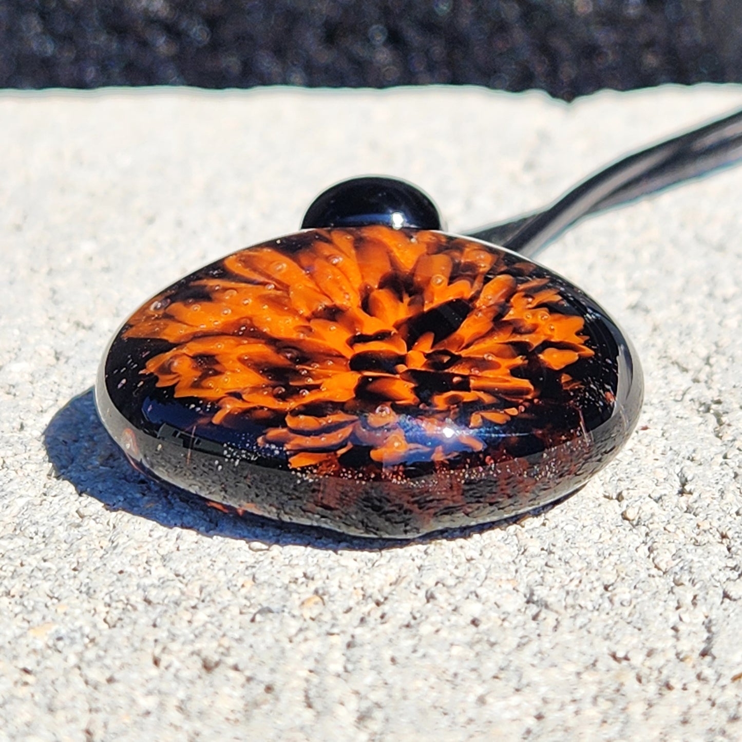 Flat-lay of the Fiery Glass Pendant Necklace showing the vibrant orange and red bloom pattern. One-of-a-kind handmade glass jewelry for autumn.