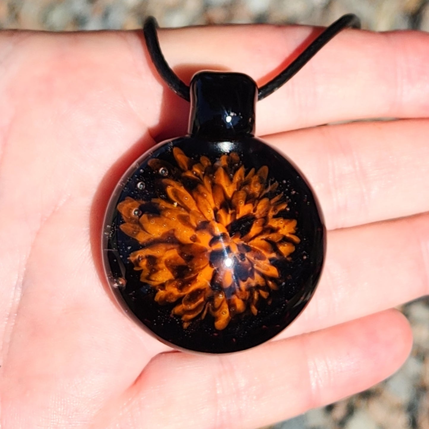 Front view of the Fiery Glass Pendant Necklace in hand, showcasing the detailed orange and red fire bloom. Unique handmade Halloween jewelry gift.