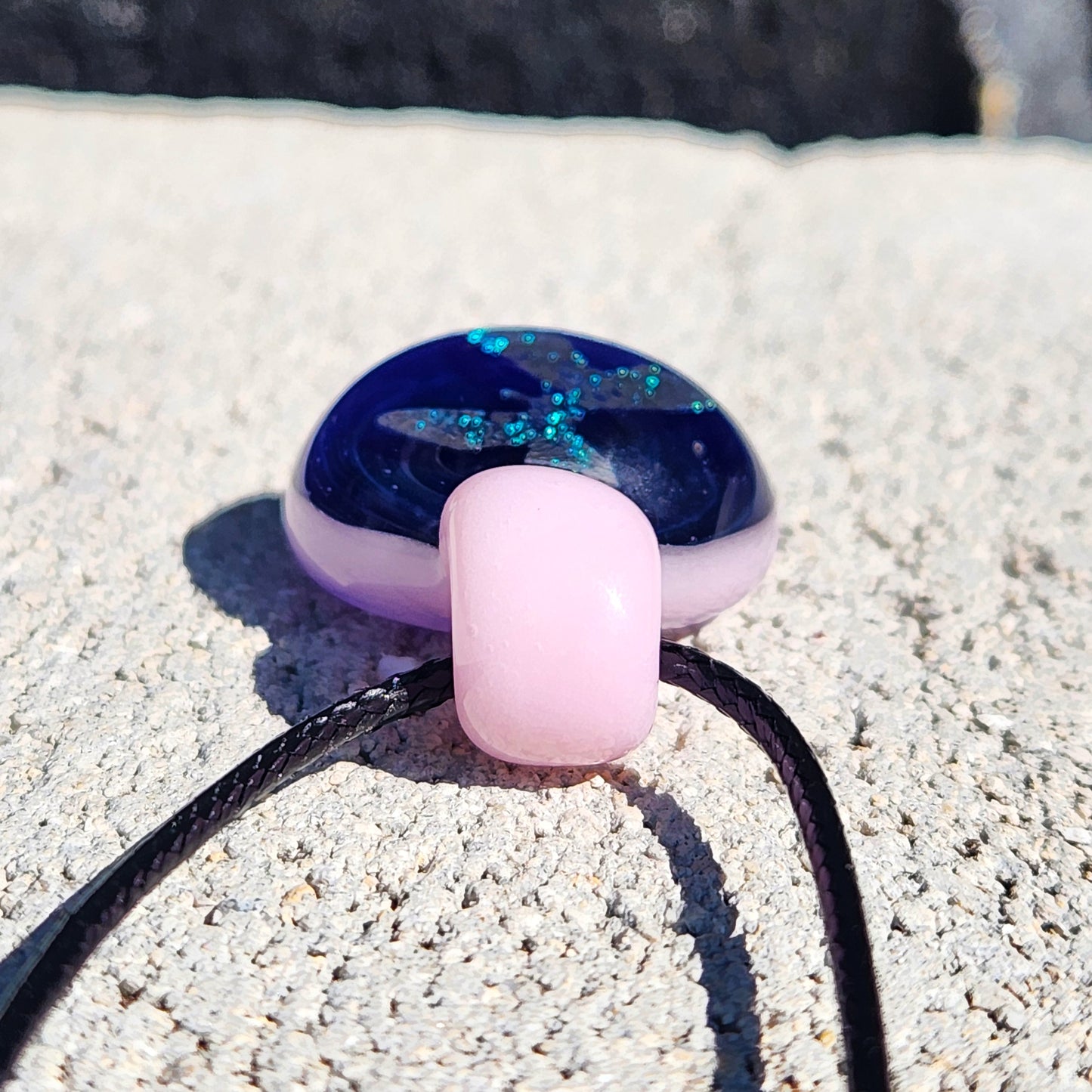 Bottom view of pink glass loop on small butterfly pendant necklace, emphasizing craftsmanship and smooth finish.