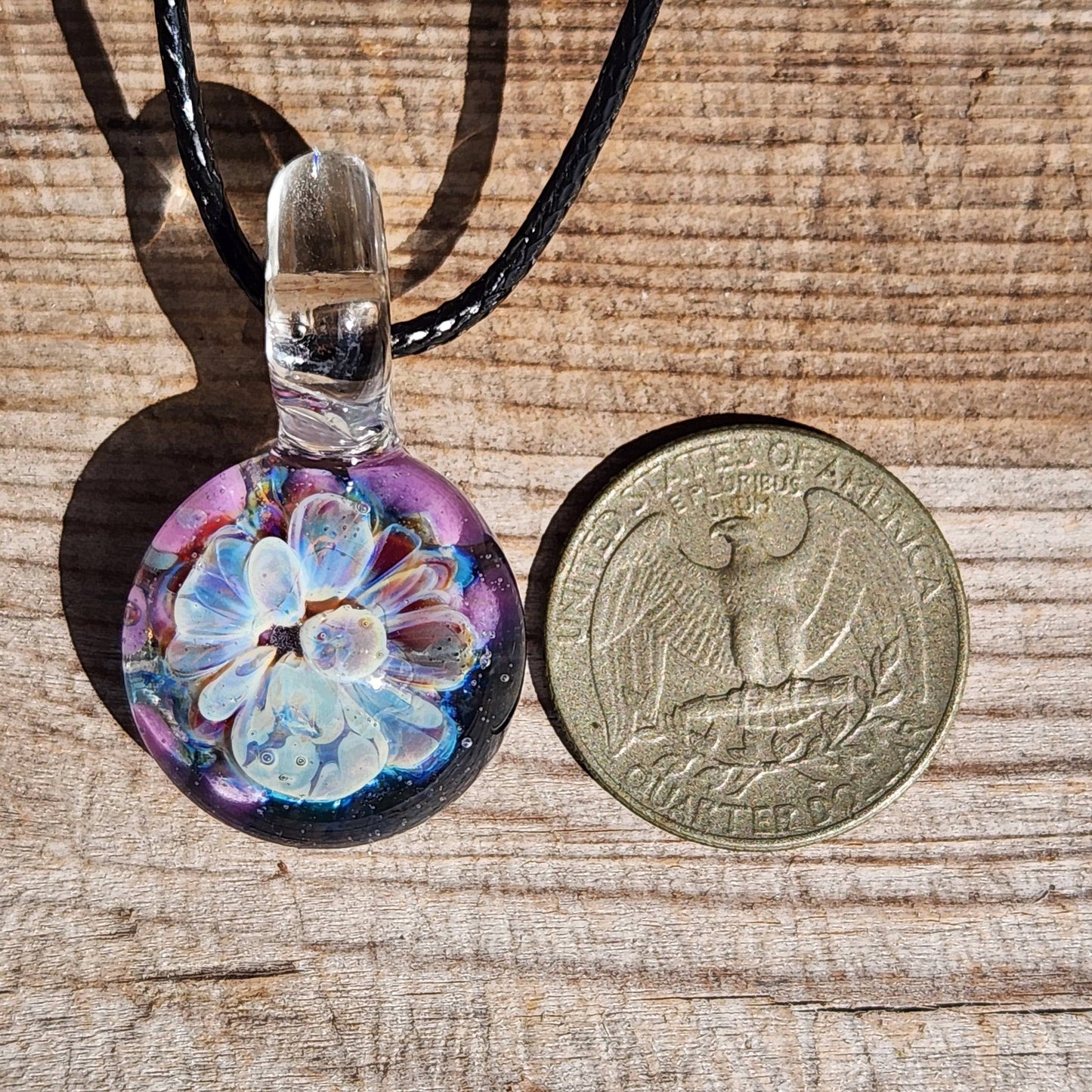 Handmade Borosilicate Glass Pendant next to a US quarter for size comparison, featuring blue and purple bloom design.