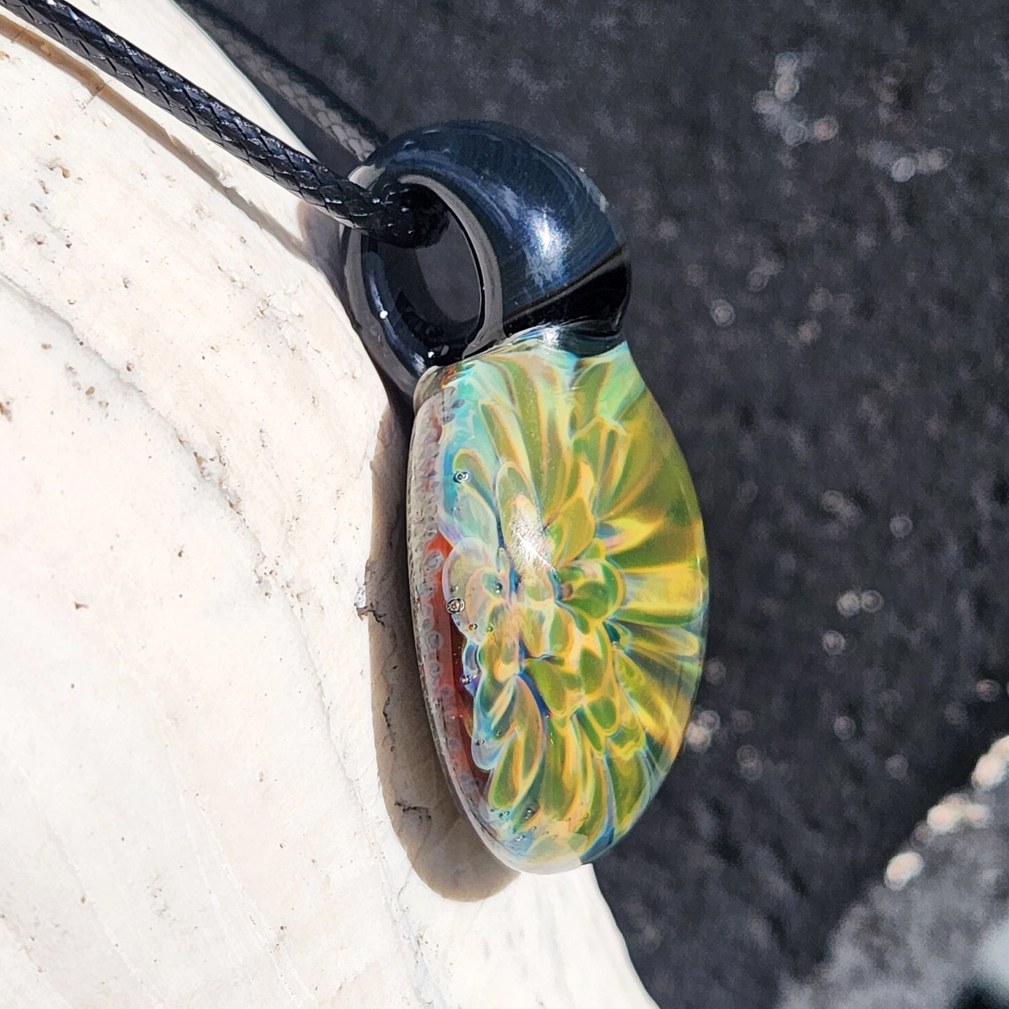 Side view of handmade glass pendant necklace showing yellow-green borosilicate flower design. Part of apparel & accessories jewelry collection.