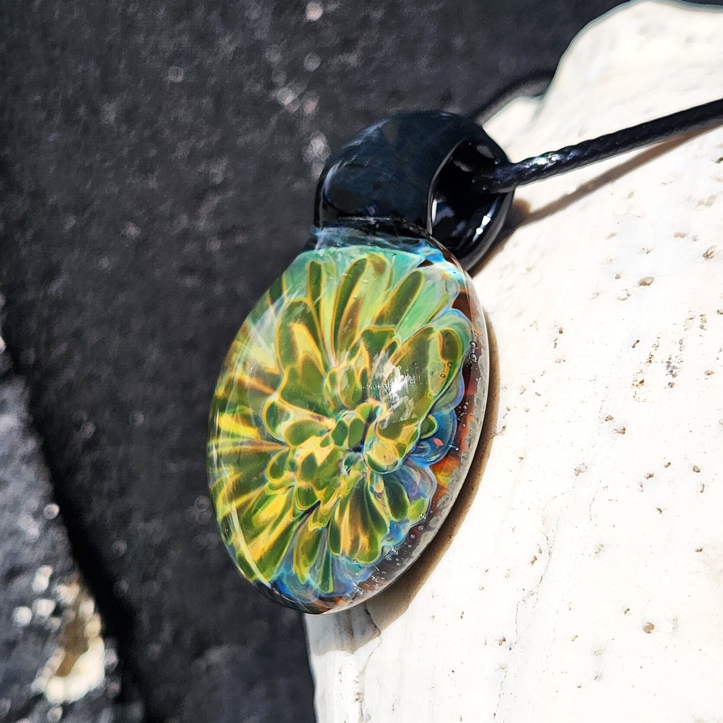 Close-up angled view of handmade glass pendant with vibrant yellow-green flower encased in clear glass. Unique gift boxed necklace.