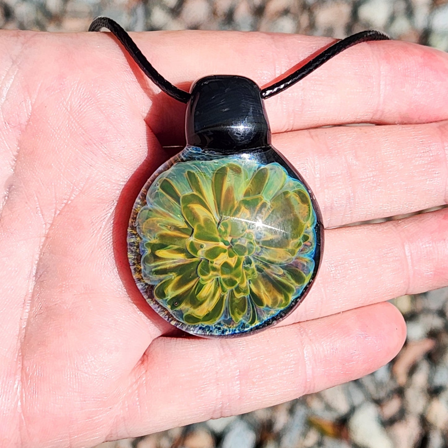 Hand displaying handmade glass pendant necklace with vibrant yellow-green flower. Gift boxed jewelry in charms & pendants category.