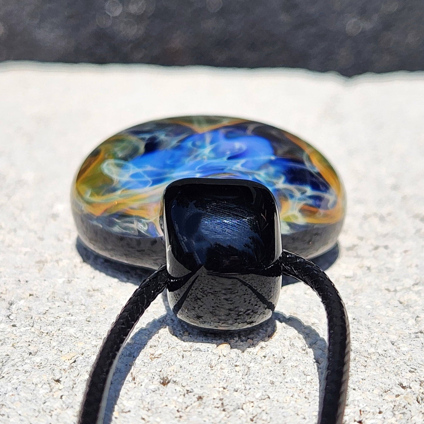 Back view of the handmade glass pendant showing glossy black loop and cord, complementing the cosmic swirl design on the front.