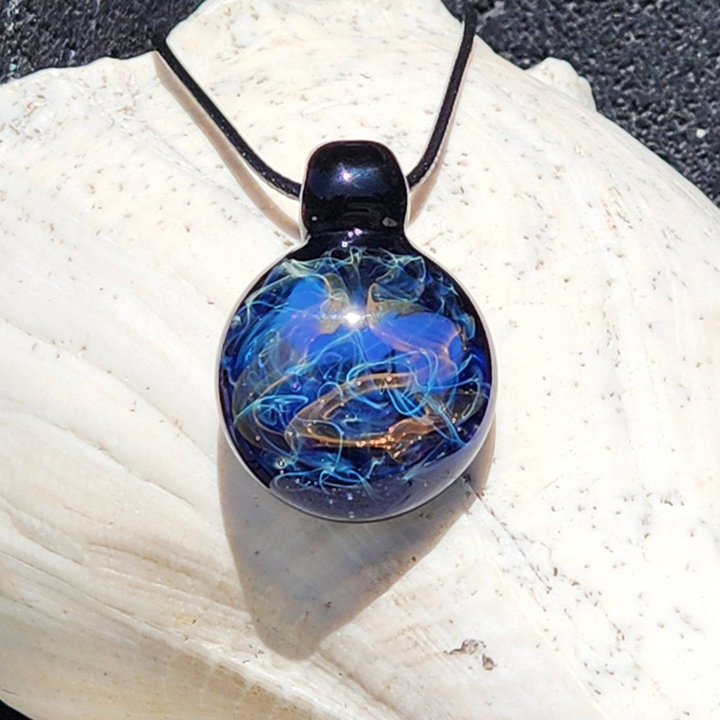 Handmade Glass Pendant – Unique Gold & Silver Fumed Black Necklace with swirling galaxy design on seashell background.