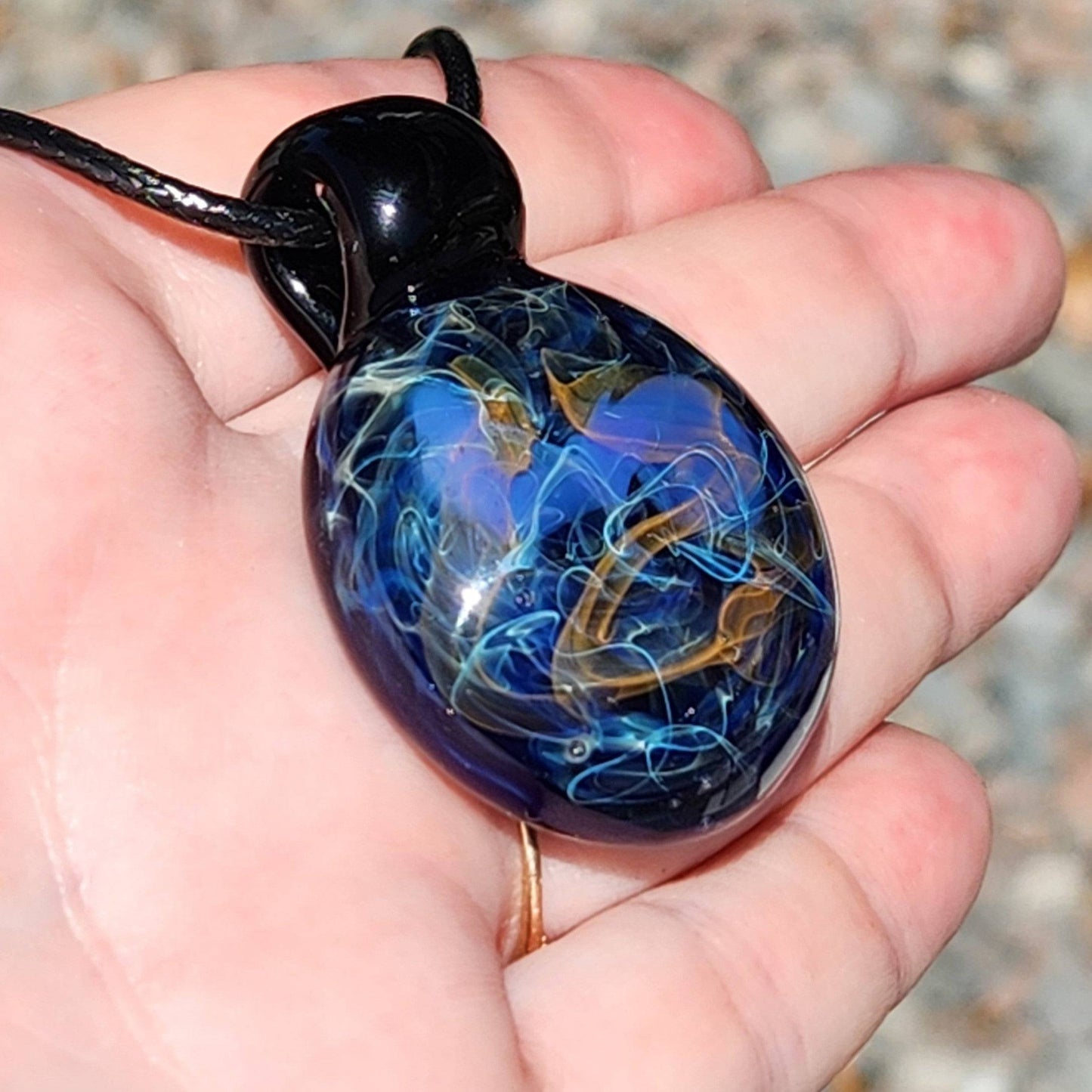 Handheld view of Handmade Glass Pendant – Unique Gold & Silver Fumed Black Necklace showing size and color vibrancy.