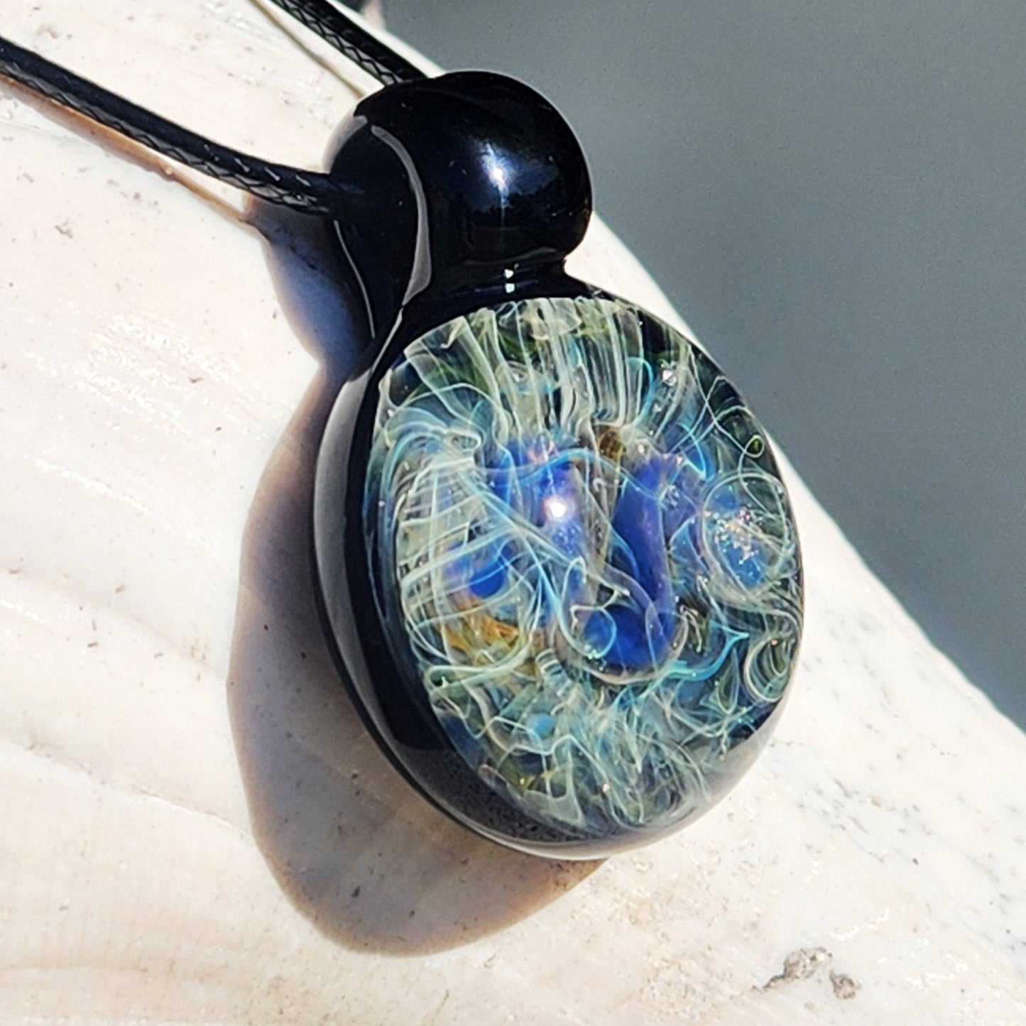 Heady glass pendant necklace with swirling blue, gold, and silver design, handcrafted in the USA. Unique handmade jewelry with cosmic glass art.