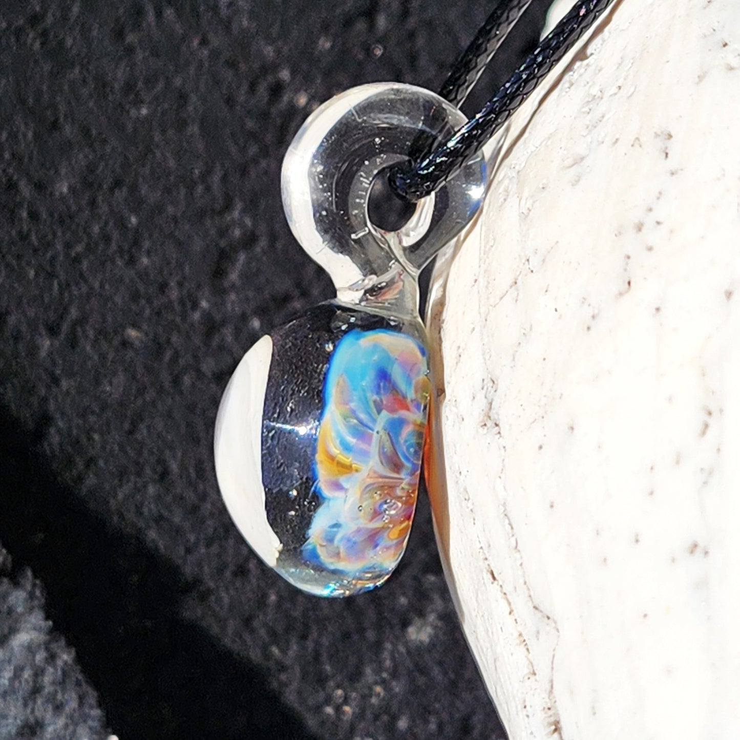 Close-up side angle of UV Glow Glass Pendant with visible loop and colorful flower core. Unique handmade jewelry for gifting or festivals.