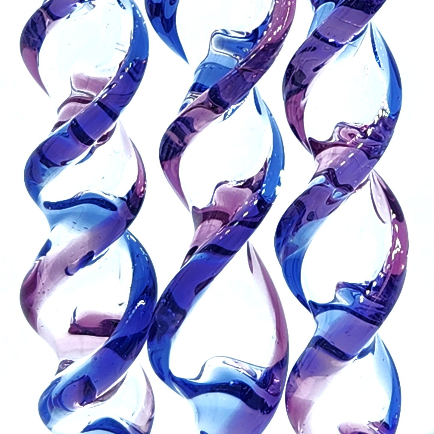 Close-up of spiral details on handmade blue and purple glass Christmas ornaments, highlighting the craftsmanship and color blending.