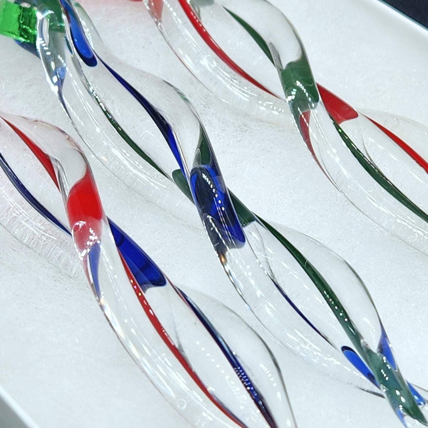 Detailed view of twisted glass icicle ornaments with vibrant red, green, and blue swirls. Elegant and festive holiday decorations.