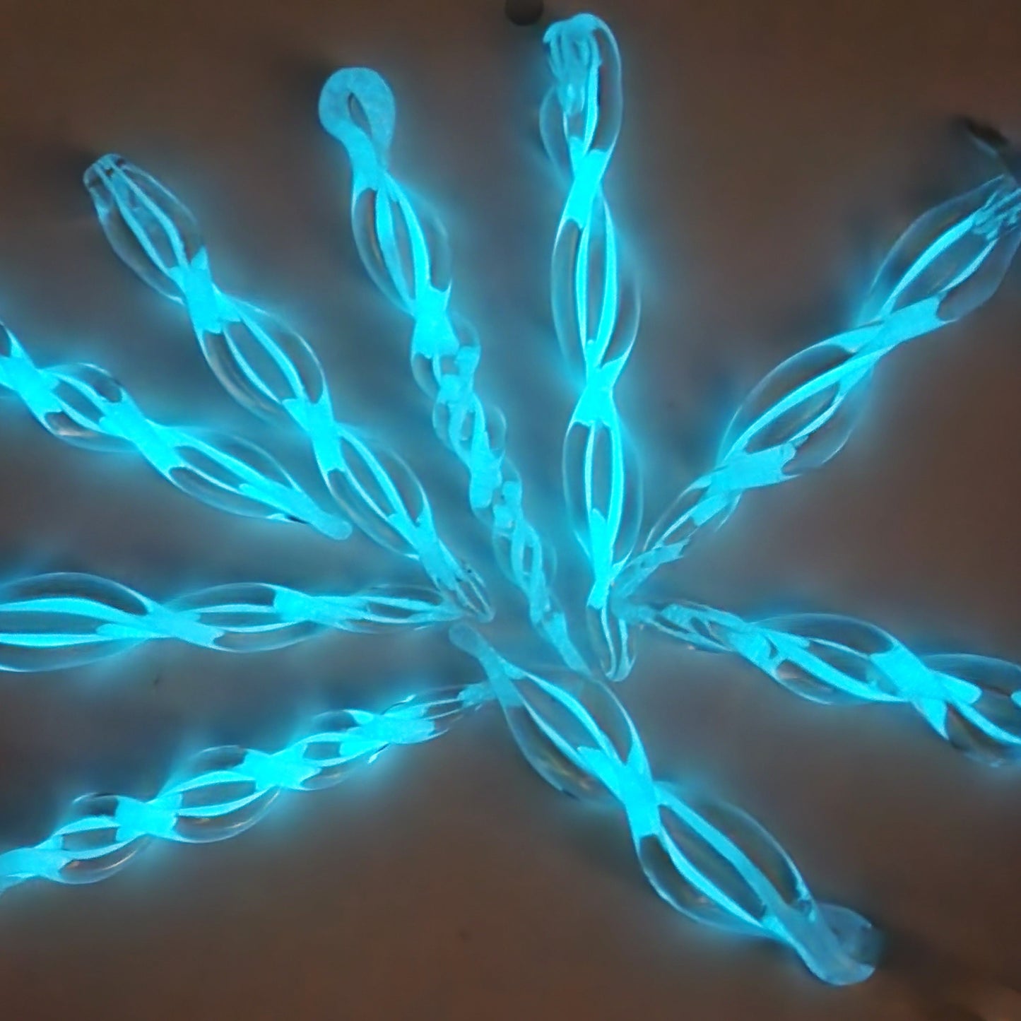 Glow-in-the-dark Christmas tree glass ornaments shaped like twisted icicles with bright blue spiral designs. Unique holiday decor for seasonal displays.