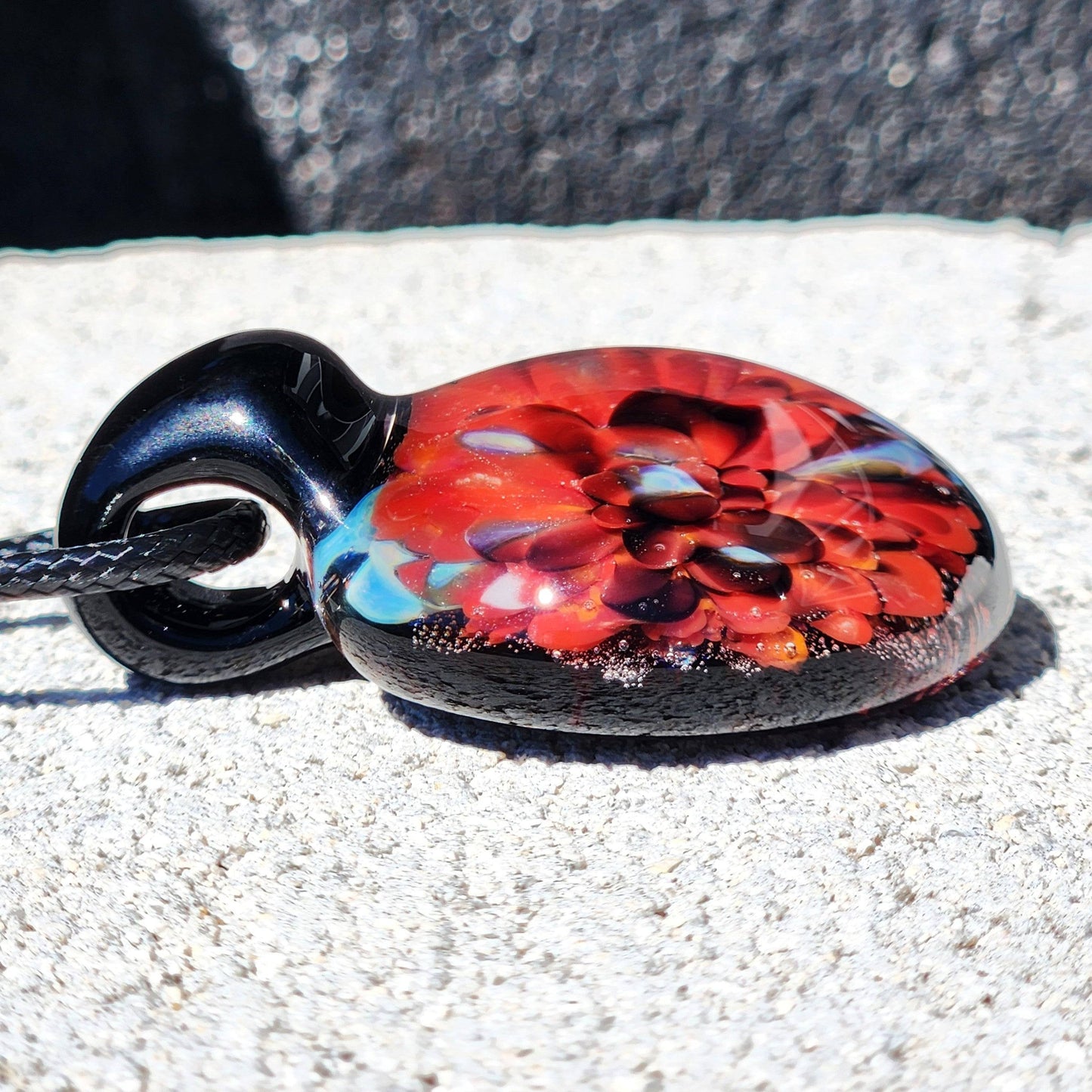 Side view of red flower glass pendant showcasing depth and clarity. Unique handmade borosilicate jewelry design for stylish gifting.
