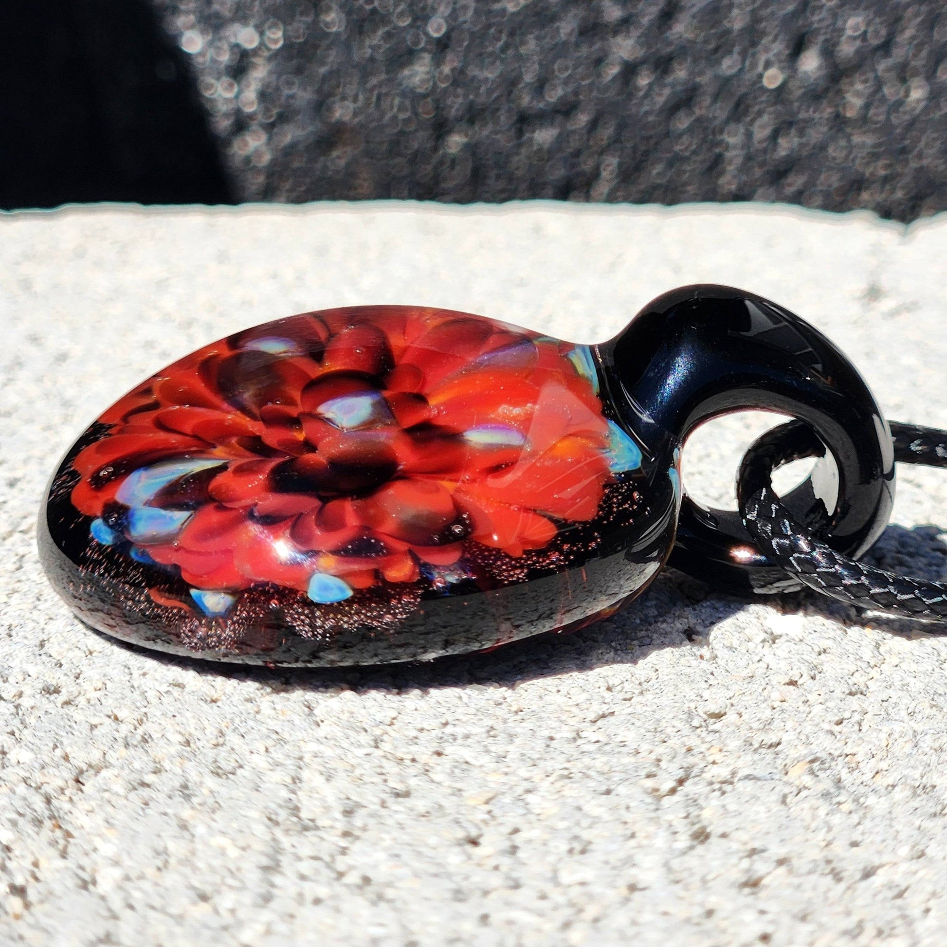 Angled view of handmade red glass pendant showing layered floral design. Durable borosilicate jewelry piece perfect for gifting or daily wear.