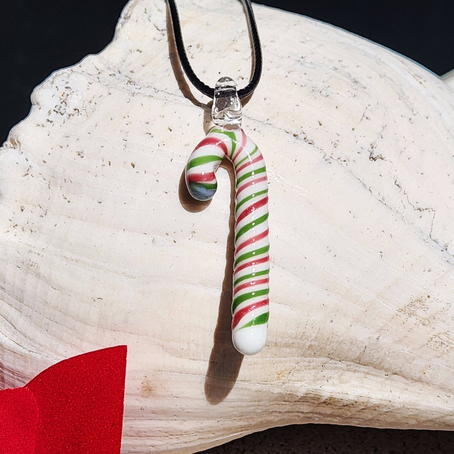 Close-up of handmade glass candy cane pendant necklace in holiday colors, ideal for festive outfits and Christmas gift giving.