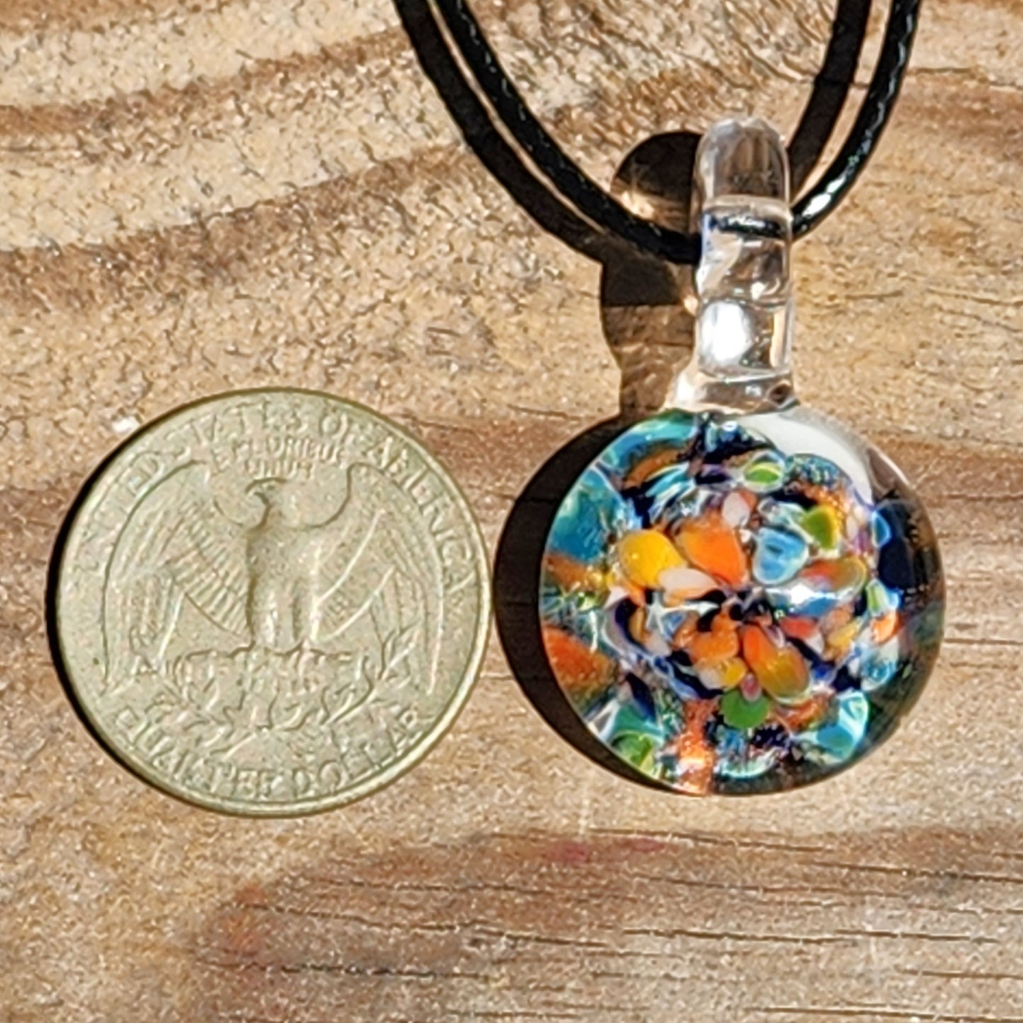 Colorful glass pendant next to USA quarter