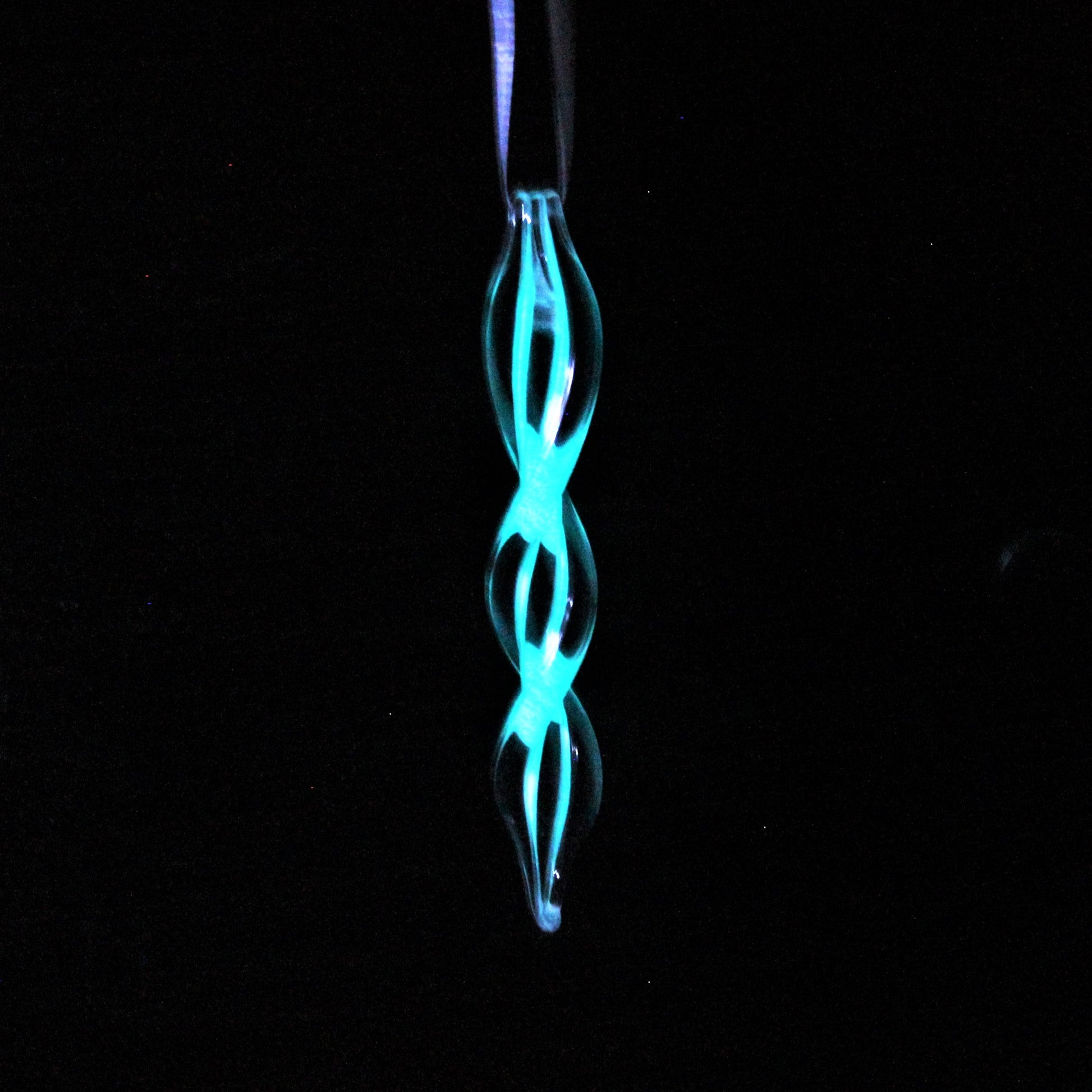 Handmade glass ornament glowing in the dark with a double helix design. Perfect for holiday gifts or seasonal home decorations.