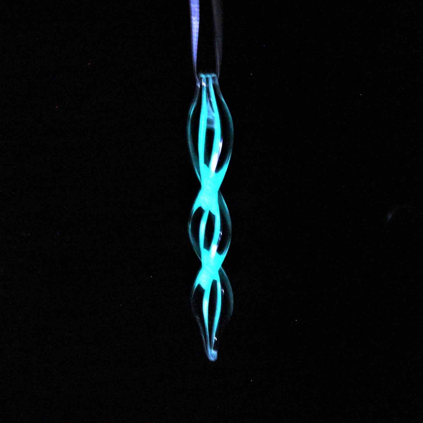 Handmade glass ornament glowing in the dark with a double helix design. Perfect for holiday gifts or seasonal home decorations.