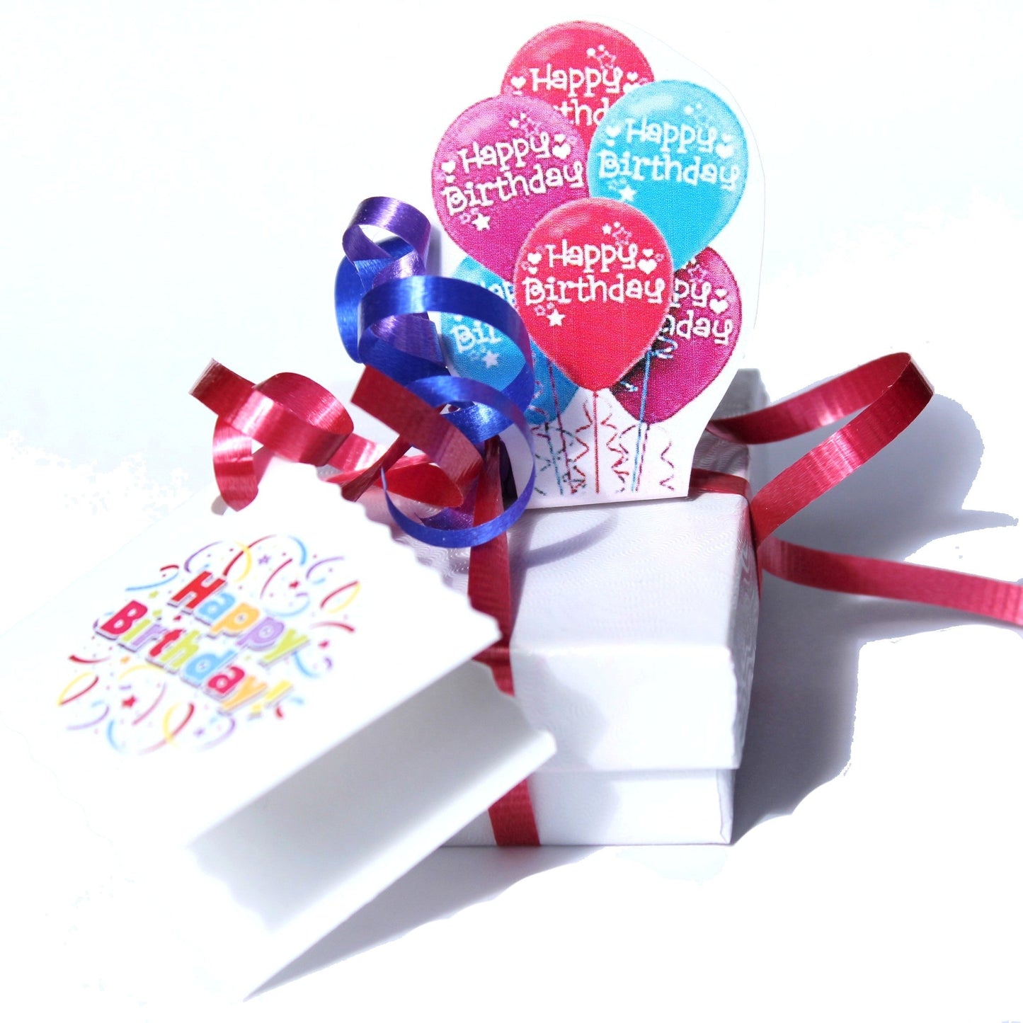 Birthday-themed elegant gift wrapping with colorful balloon cutouts and red ribbon on a white box. Celebrate every occasion in style.
