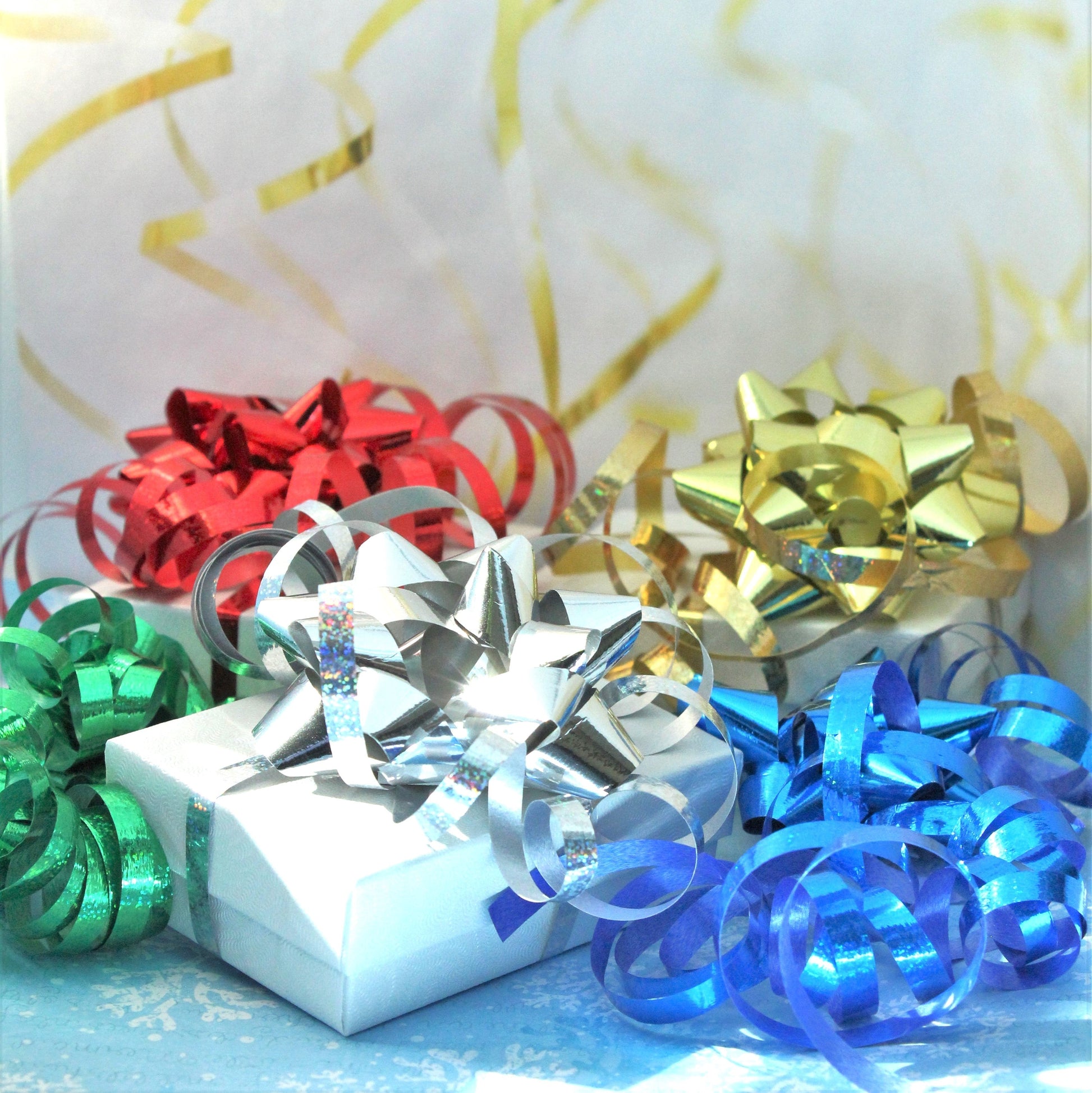 Holiday-themed elegant gift wrapping with metallic bows in red, green, silver, gold, and blue on a white box. Celebrate every occasion in style.