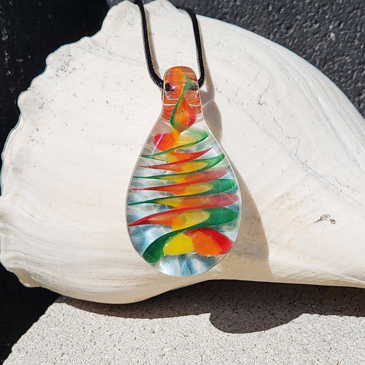 Handmade glass pendant necklace with spiral rainbow design displayed on a white seashell. Vivid colors swirl inside the teardrop-shaped glass.
