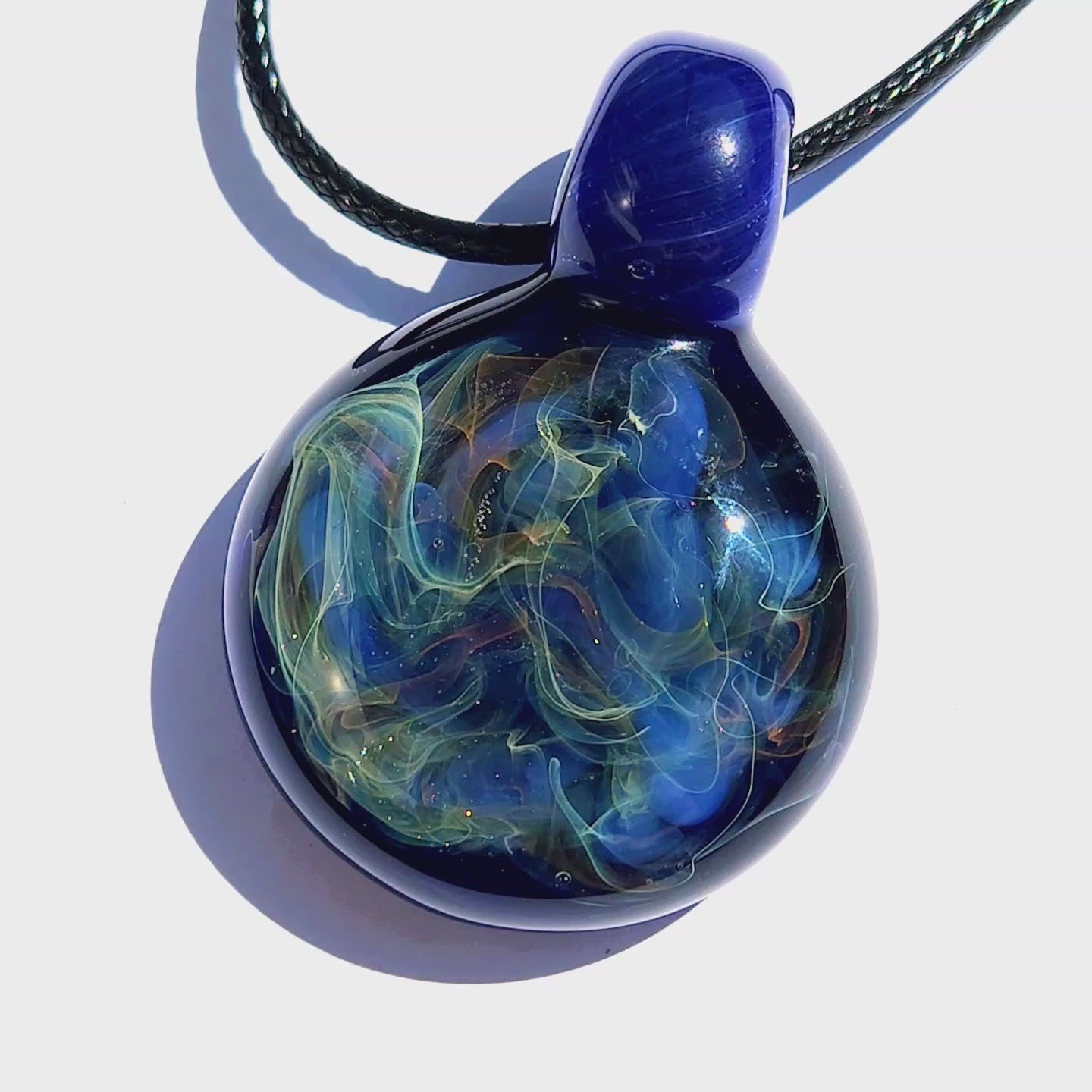 Close-up of trippy blown glass pendant necklace with vivid blue and silver-gold fumed design, handcrafted for unique style.