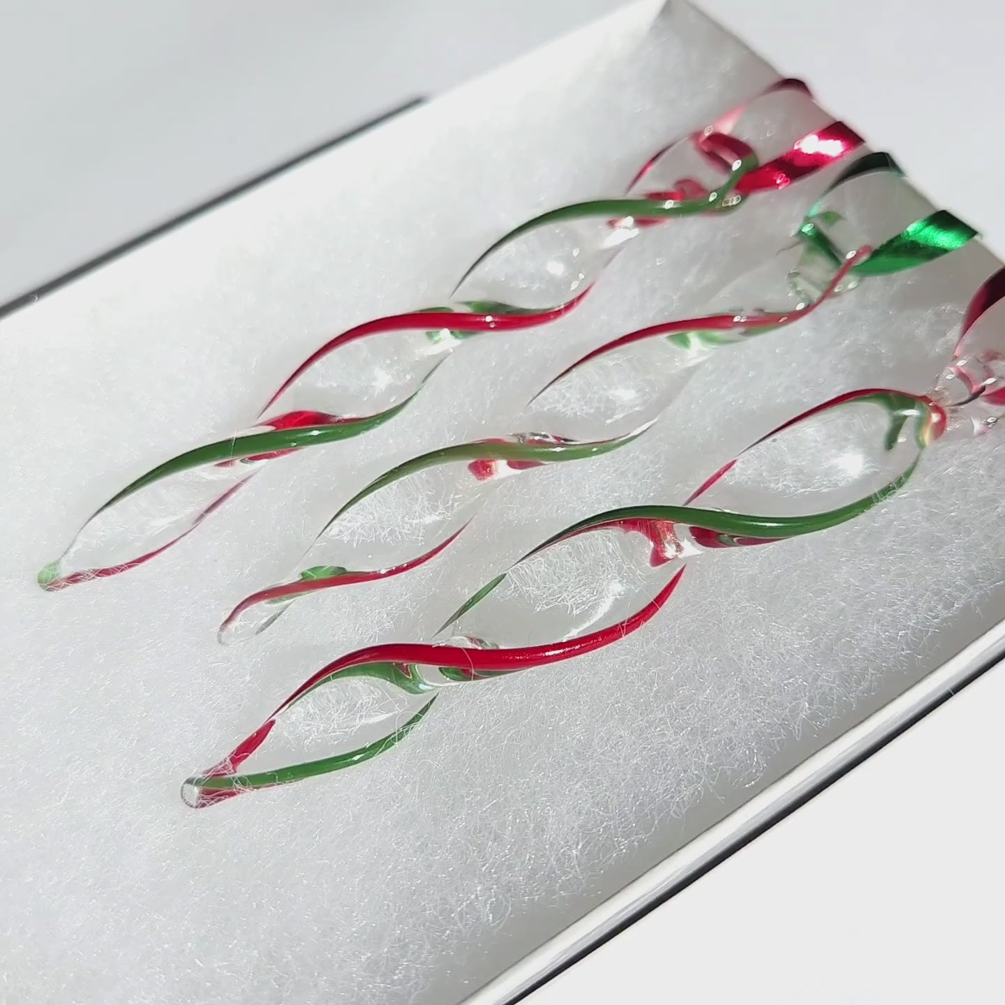Detailed view of Unique Handmade Glass Icicle Ornaments - Festive 3-Piece Ornament Set with vibrant red and green swirls on clear glass.
