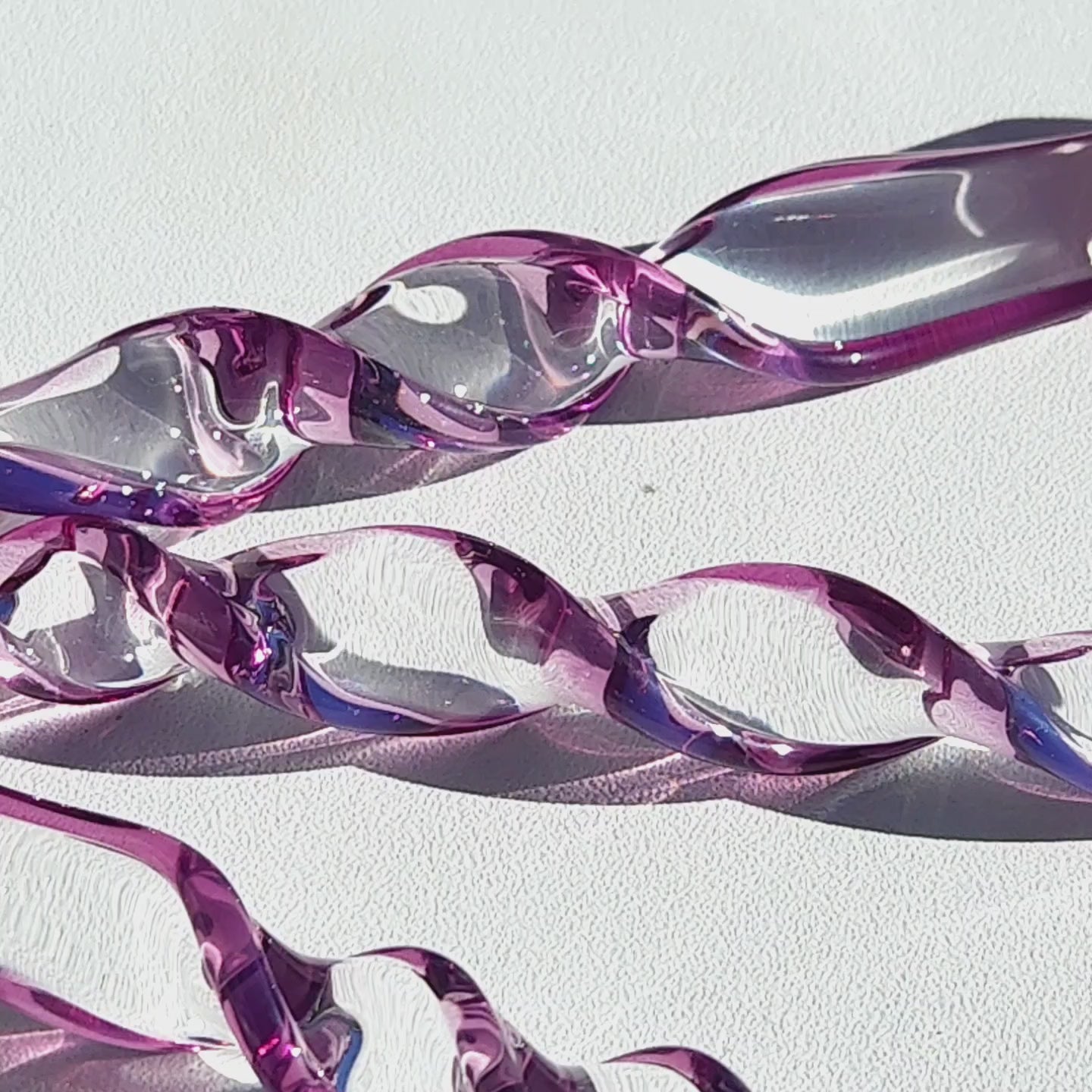 Close-up of purple spiral glass suncatchers showing detailed twists and reflections, ideal for garden or patio hanging decor.