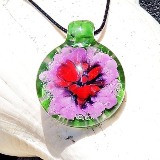 Large Heady Glass Pendant Necklace featuring a red and purple flower design encased in green blown glass. Handmade jewelry art with bubble accents.