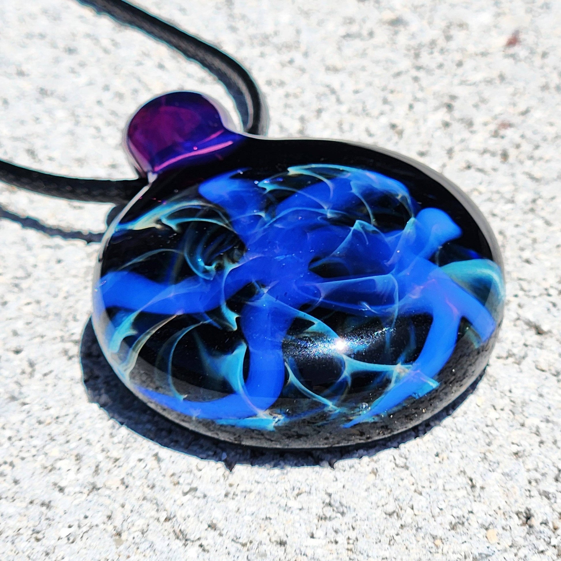 Unique Handmade Blue Swirl Glass Pendant Necklace featuring vivid blue and teal swirls on a black base with a purple loop.