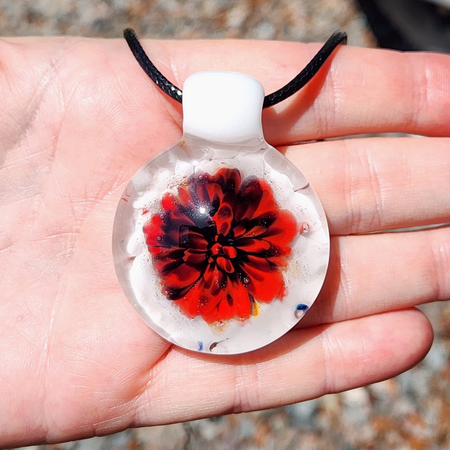 Hand holding Red Flower Glass Pendant Necklace, showcasing the handmade floral design and scale of the jewelry piece.