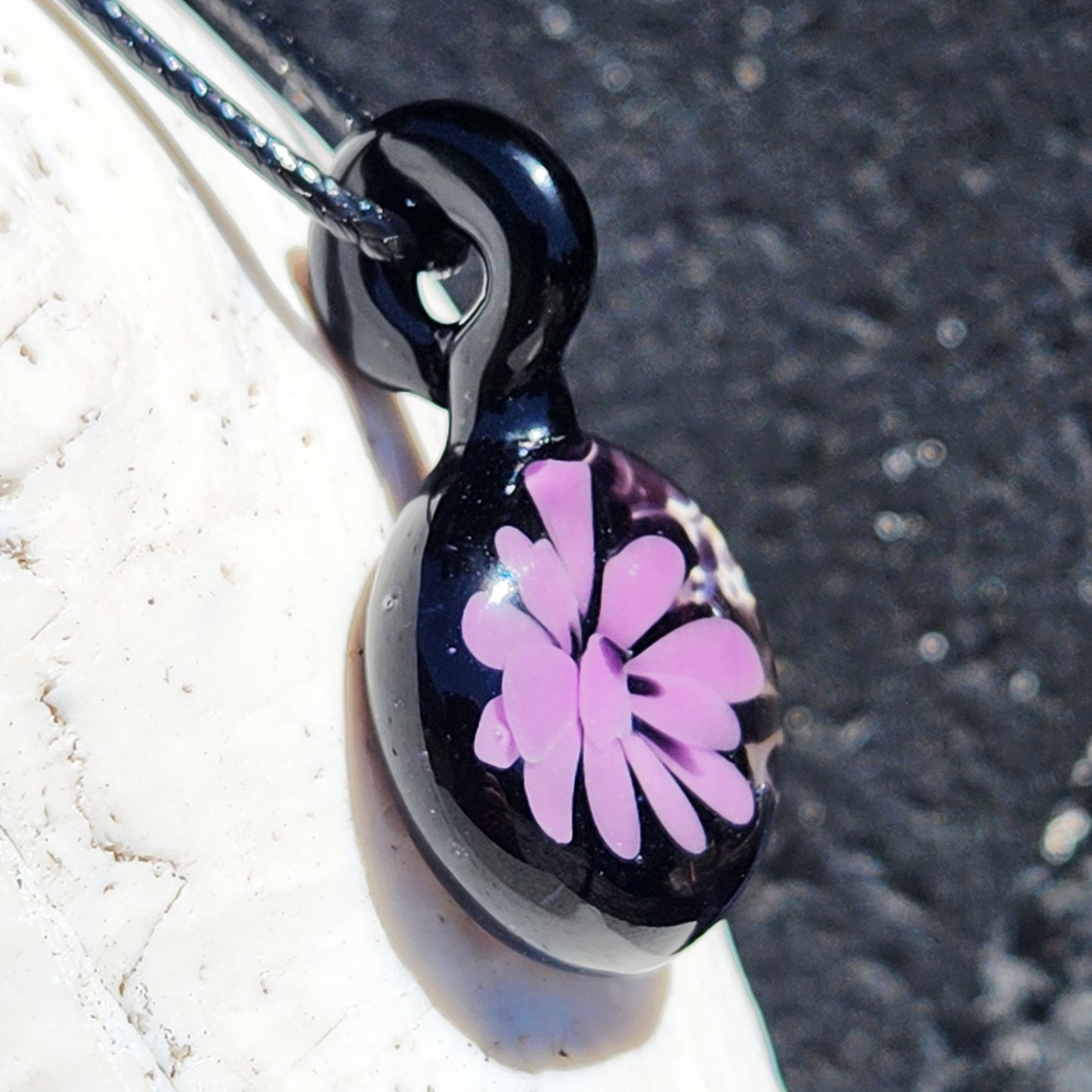 Angled view of handmade purple and black glass pendant necklace, featuring a floral design, great for gifting or personal accessories.