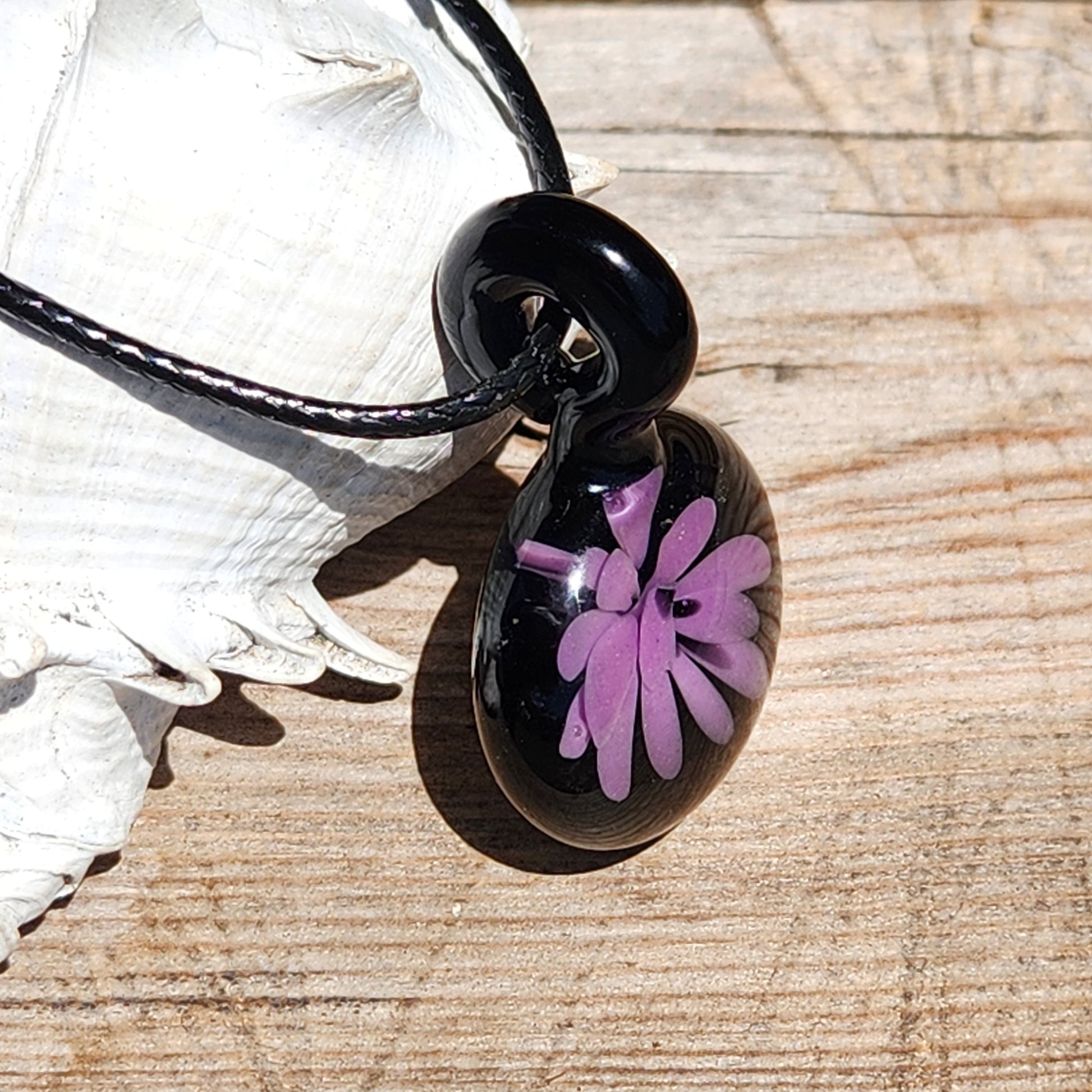 Side view of handmade black and purple glass pendant necklace, featuring a floral design, perfect for minimalist statement jewelry lovers.