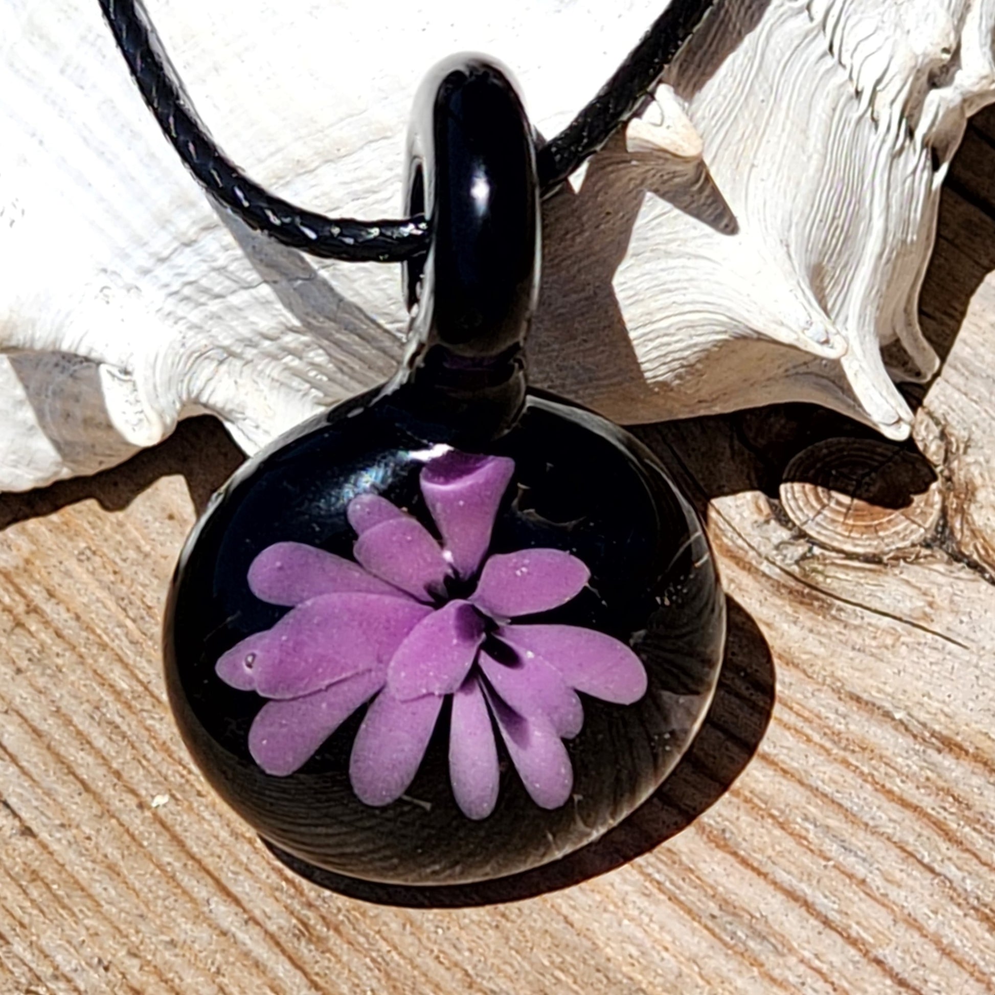 Handmade purple and black glass pendant necklace with floral design, shown on wood background, ideal for unique gift jewelry shoppers.