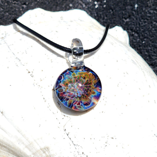 Ocean Reef Glass Pendant Necklace with vibrant blue, green, and red borosilicate glass on black cord, displayed on white shell background.
