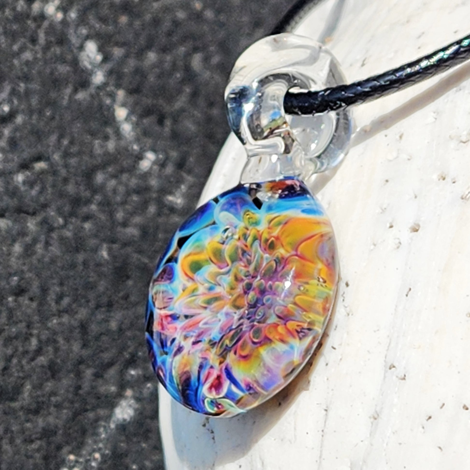 Close-up of Ocean Reef Glass Pendant Necklace showcasing intricate crushed glass pattern in vivid oceanic hues, hanging from clear loop bail.