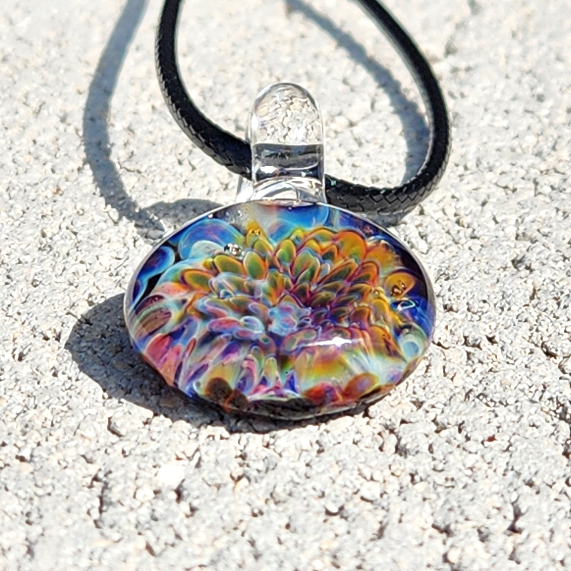 Handmade Ocean Reef Glass Pendant featuring multicolor reef-inspired design, shown on textured stone surface with black necklace cord.