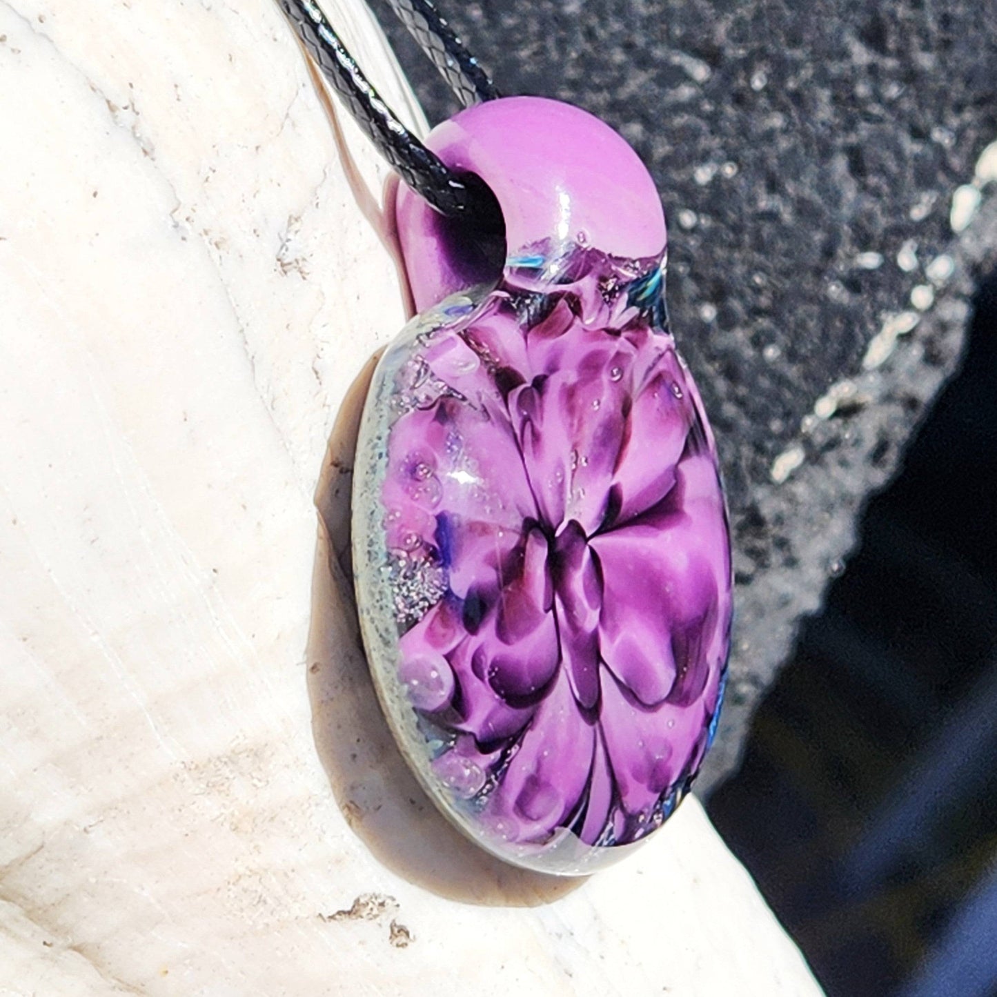 Angled view of purple and black floral glass pendant on a shell, showcasing its depth and craftsmanship. Ideal handmade gift for her.