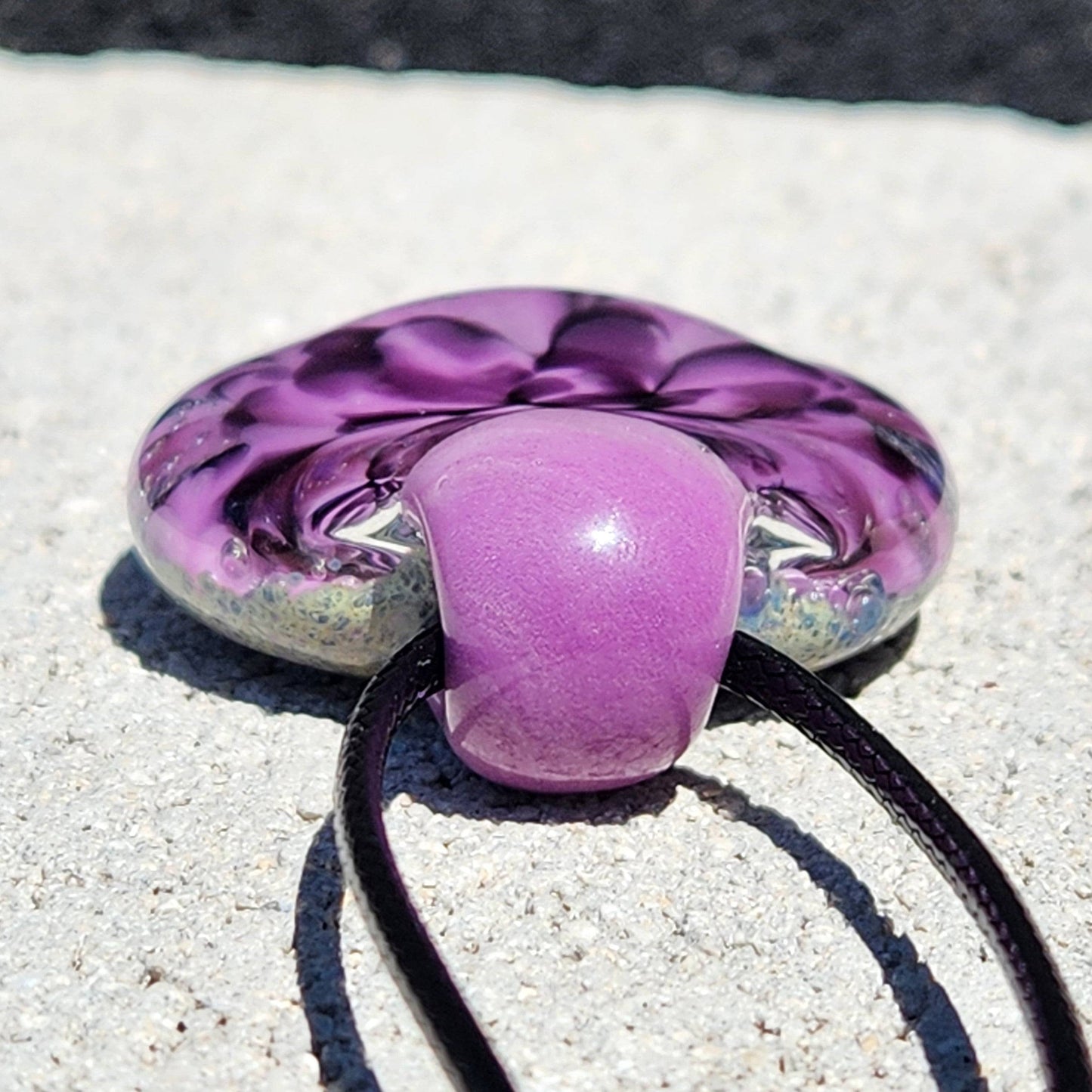 Back view of purple and black glass pendant with smooth finish and cord loop. Durable and artistic handmade jewelry piece.