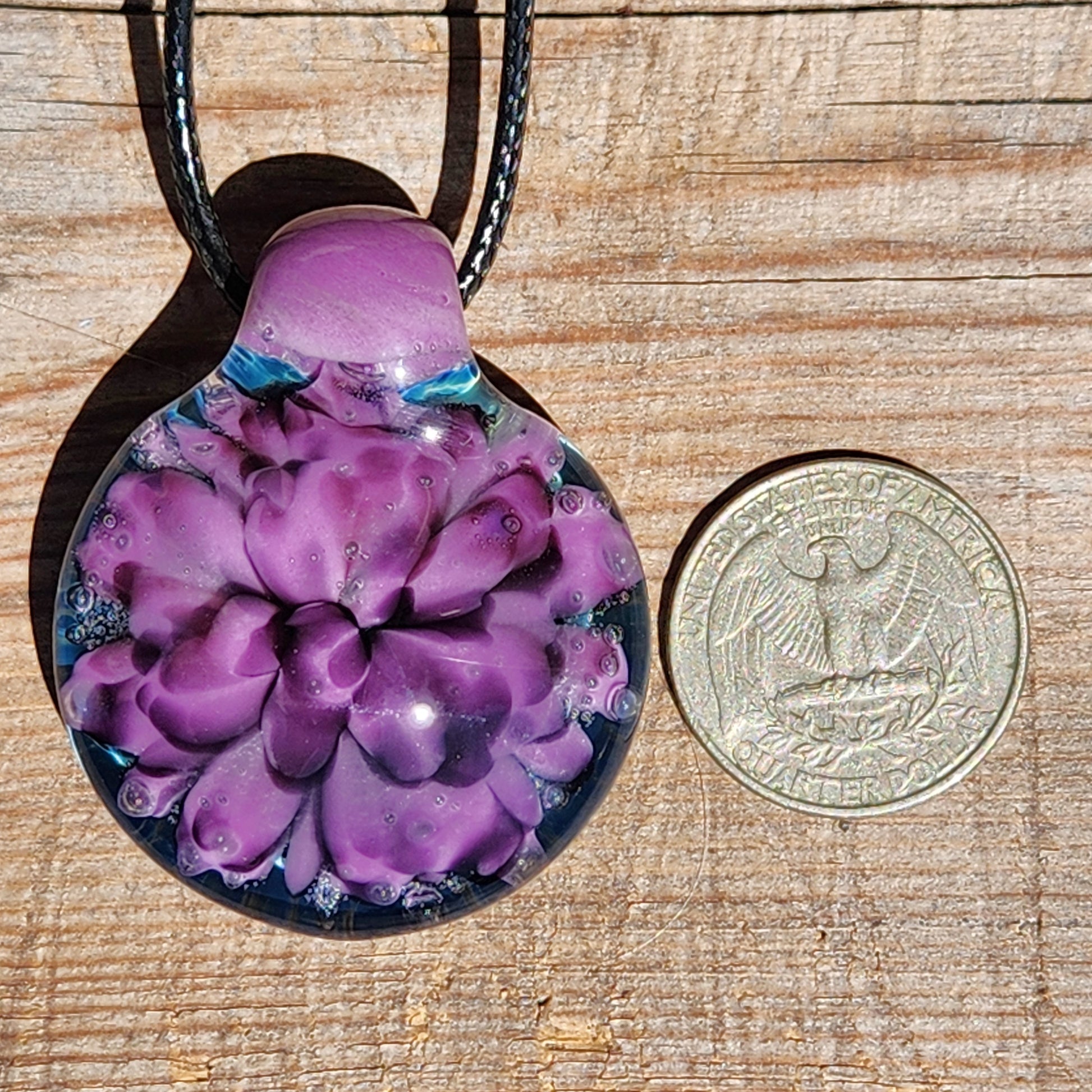 Purple floral glass pendant necklace next to a US quarter for size comparison. Handblown borosilicate jewelry gift for her.