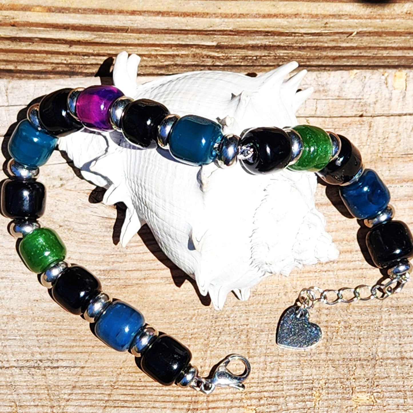 Boho Glass Beaded Bracelet with heart charm and colorful beads displayed on wood with a white seashell for contrast.