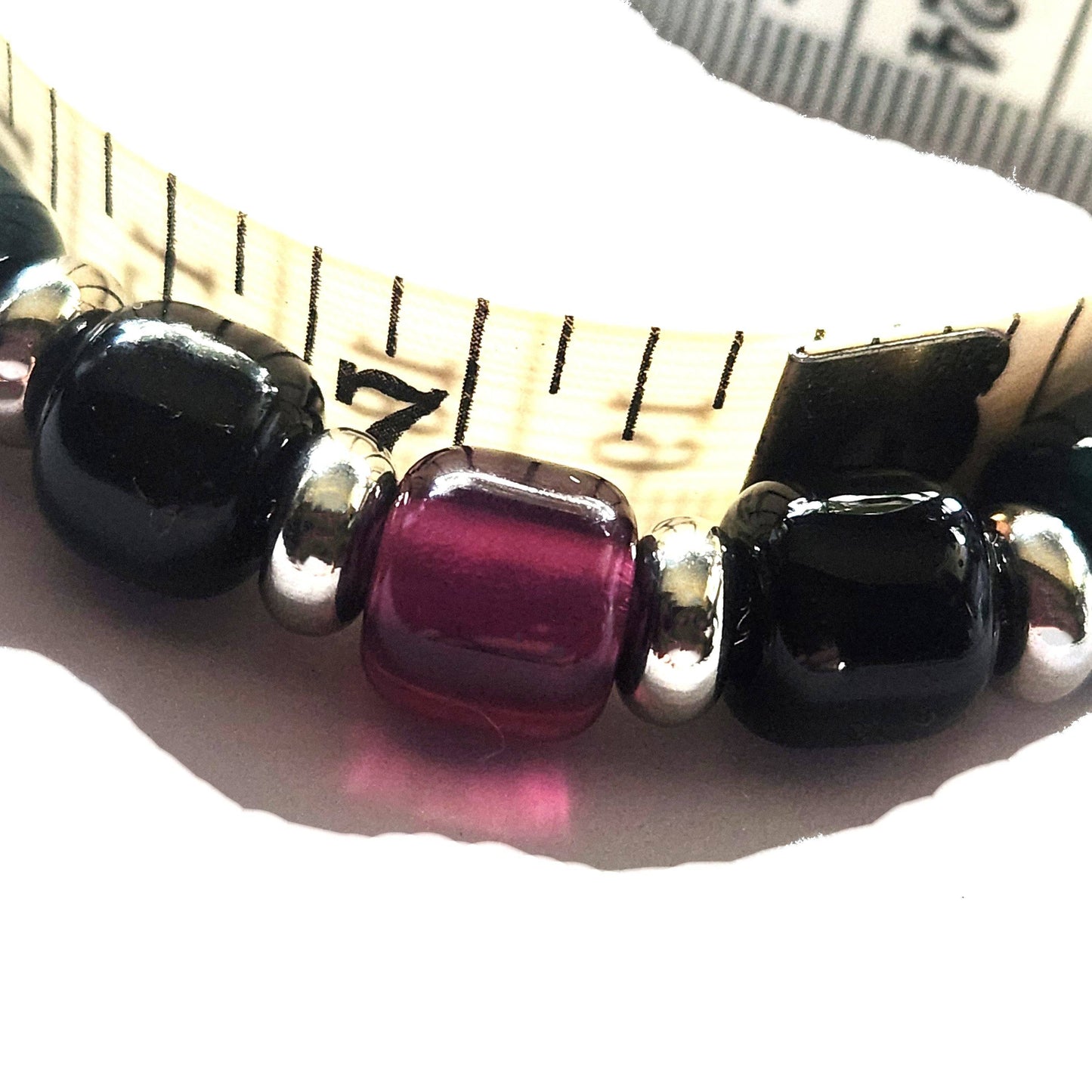 Close-up of purple glass bead on Boho Bracelet next to measuring tape, showcasing bead size and handmade detail.