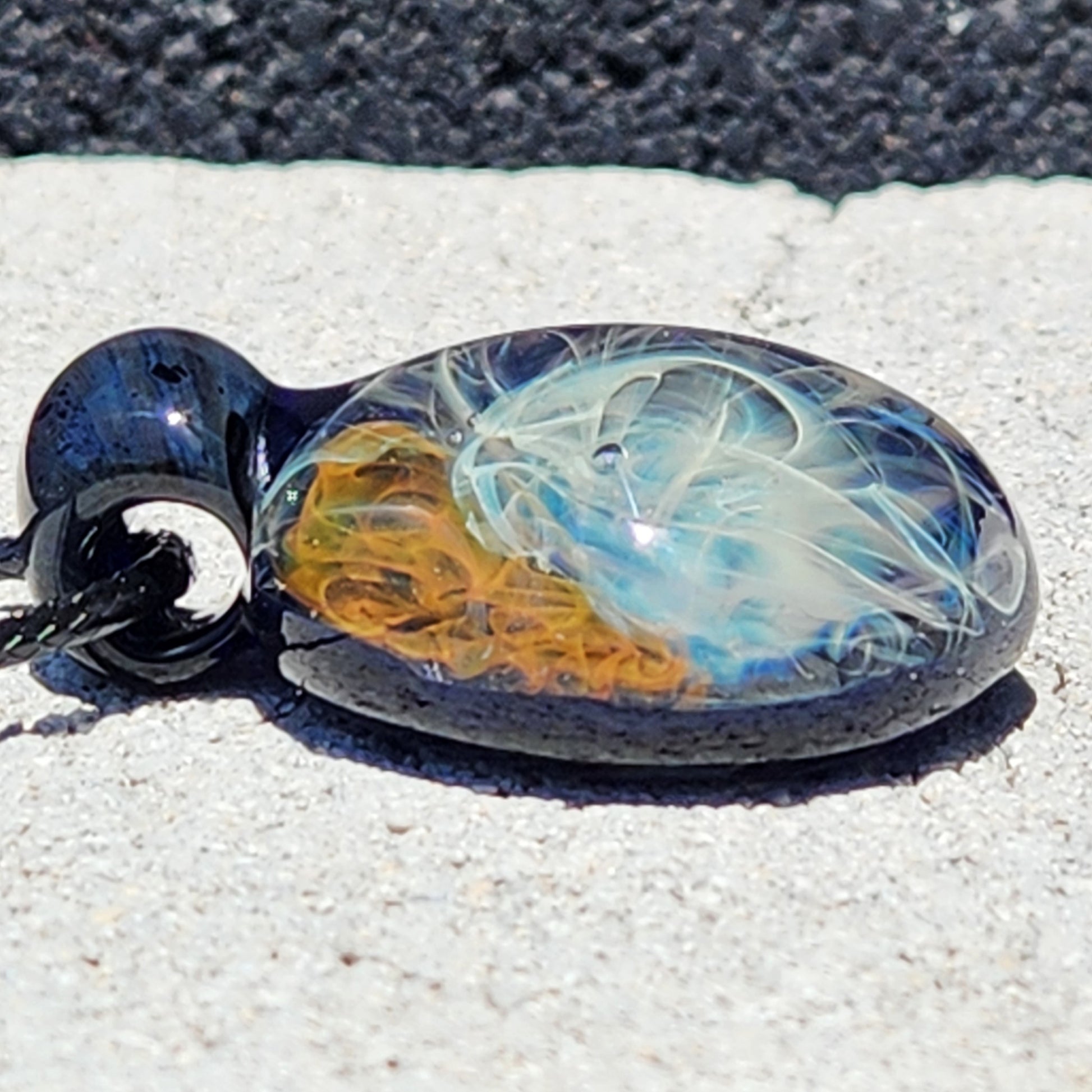 Side view of Gold & Silver Fumed Glass Pendant Necklace with detailed swirling design. Handblown glass pendant in blue, gold, and silver hues.