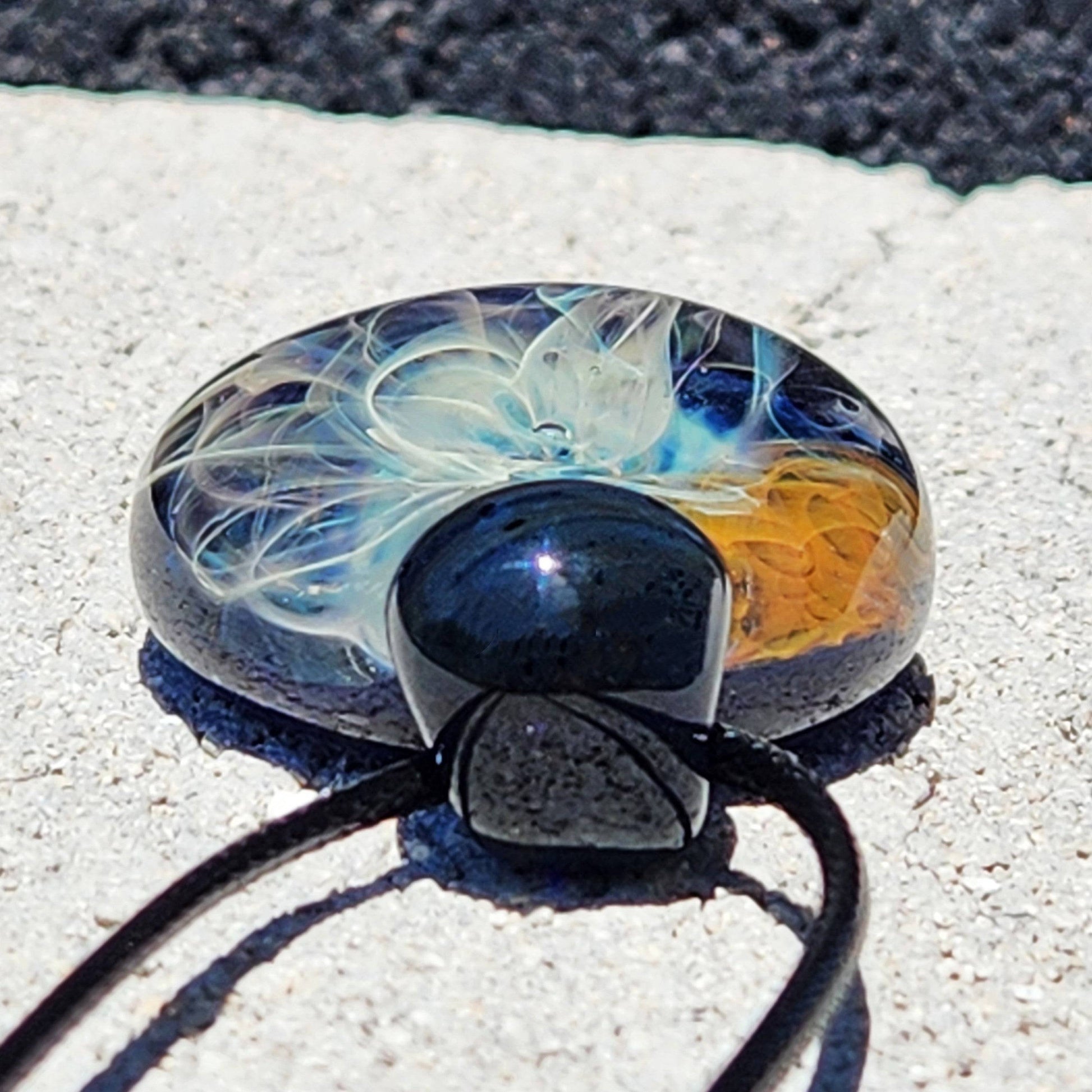 Back view of Gold & Silver Fumed Glass Pendant Necklace with black loop and cord. Features detailed glasswork in blue, gold, and silver.